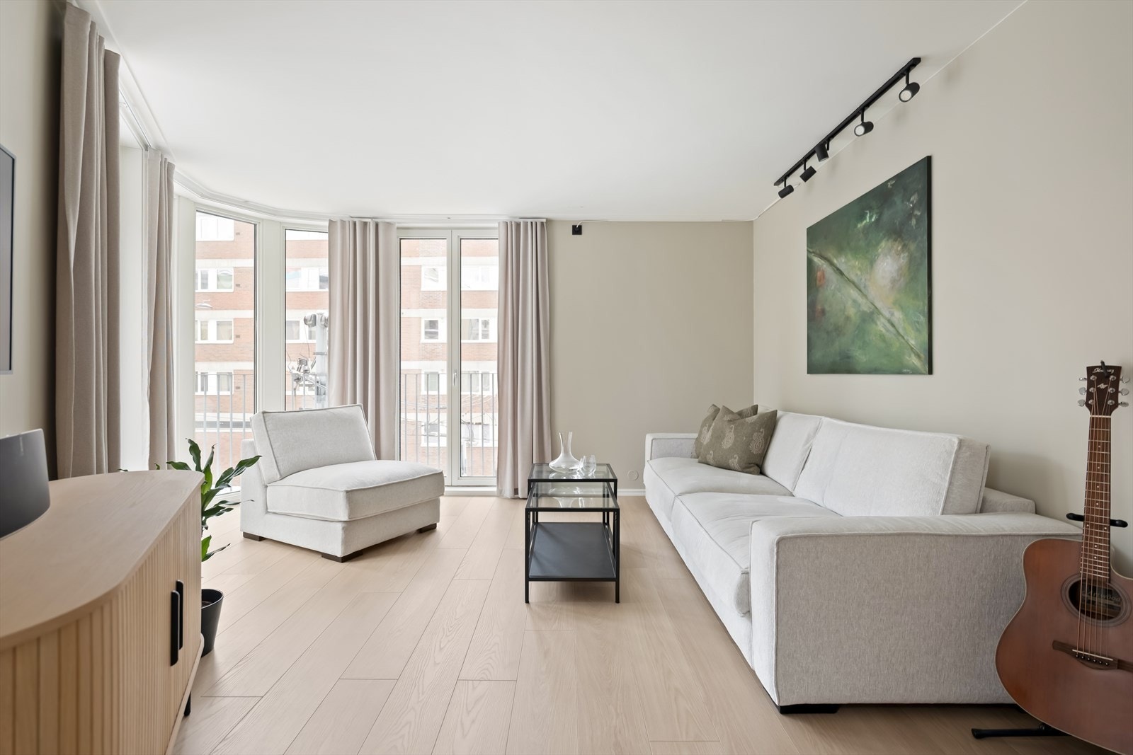 Lys og tiltalende stue med store vindusflater som følger rommets buede fasade. Galleribilde