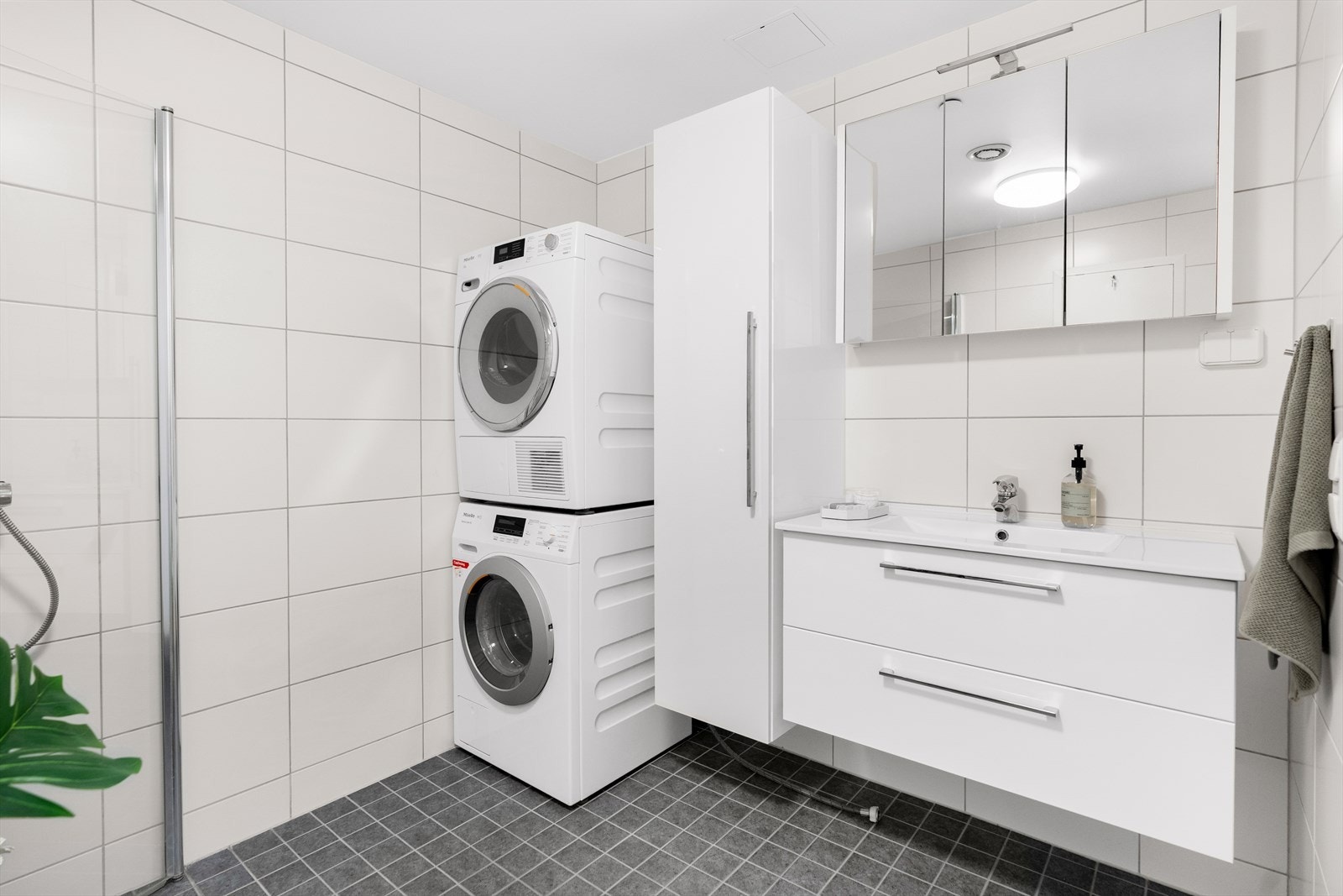 Badet har også dusjhjørne med svingdører, håndholdt dusj og termostatstyrt blandebatteri, samt veggmontert toalett. Videre er det opplegg for vaskemaskin og tørketrommel. Badet har balansert avtrekk i himling, samt plastsluk i dusjsonen. Galleribilde