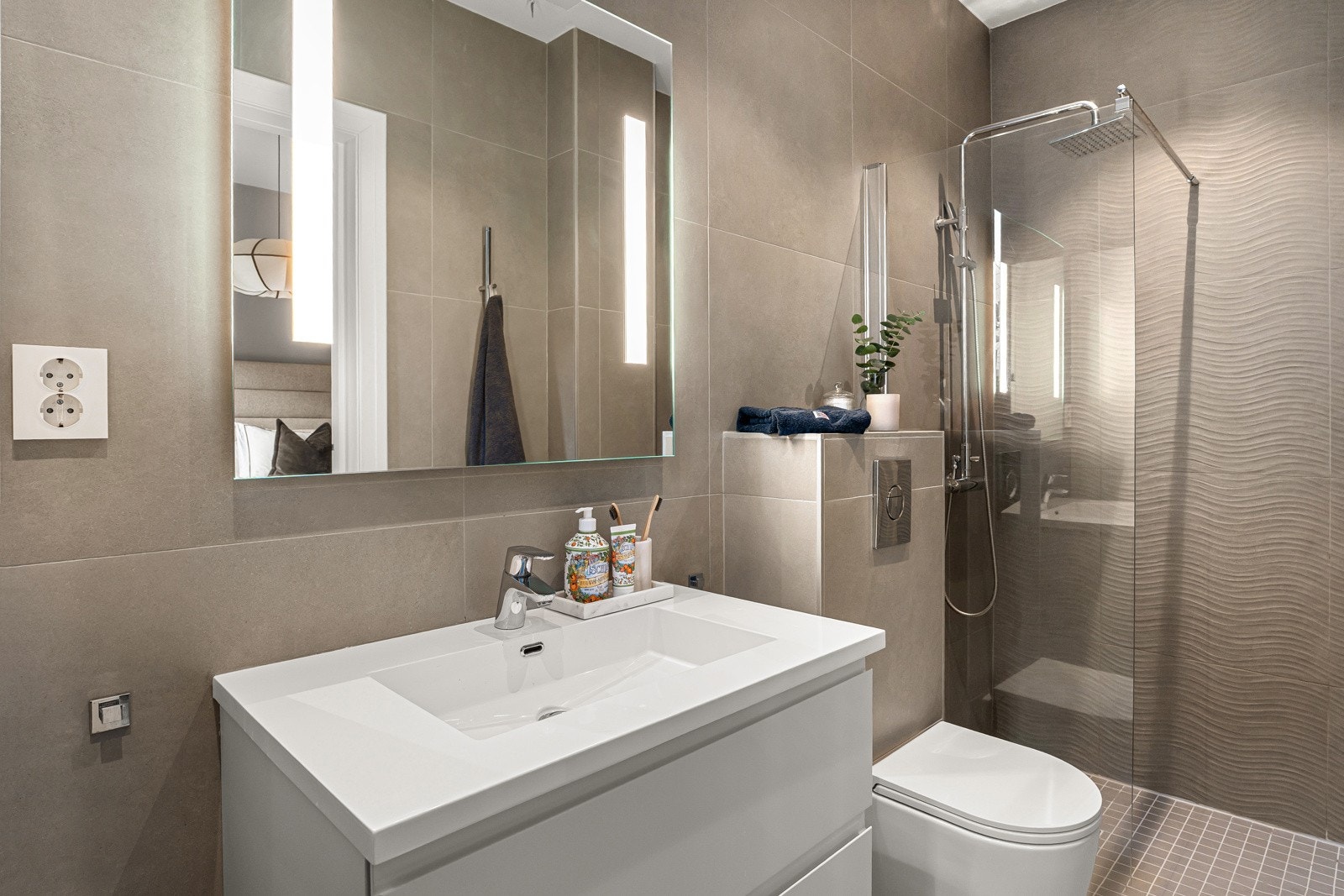 Her bys det blant annet på store fliser med behagelig gulvvarme, servantskap, servant, dusjhjørne og toalett. Galleribilde