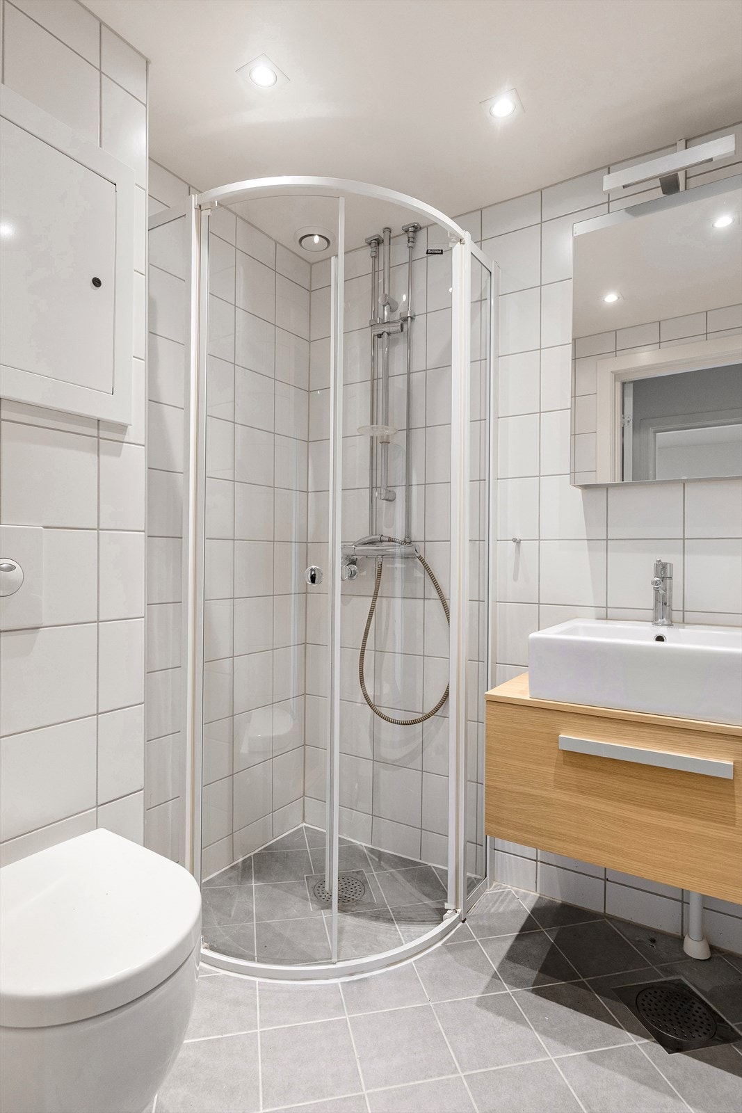 Baderommet er utstyrt med gulvvarme som ikke er funksjonstestet. Rommet har rørfordelingsskap, stoppekran og naturlig avtrekk. Det er veggmontert wc og dusjhjørne med glassdører, gulvskinne og ettgreps krummet dusjarmatur. Galleribilde