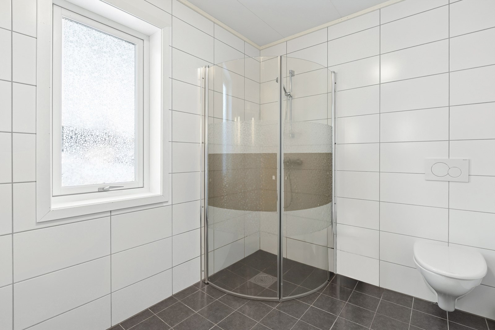 Badet er utstyrt med toalett, dusjhjørne, baderomsinnredning og opplegg til vaskemaskin. Galleribilde