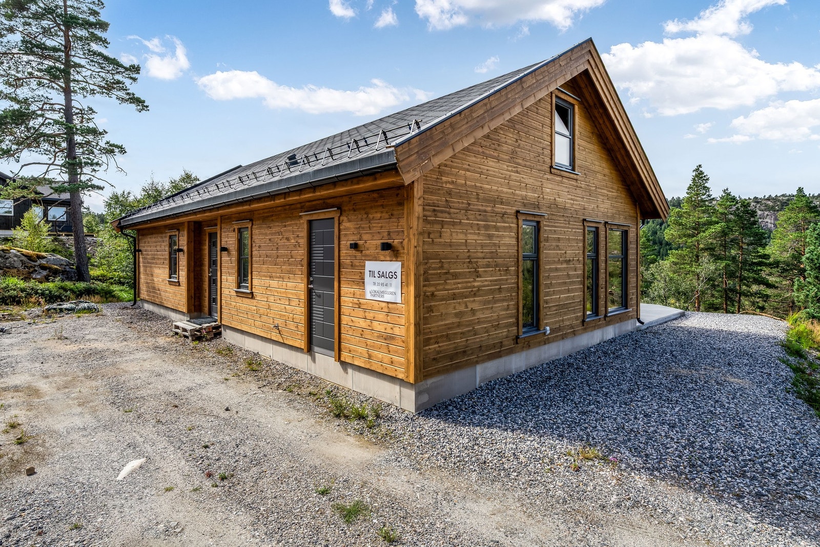 Parkering ved hyttevegg. Det er montert el-bil lader. Galleribilde