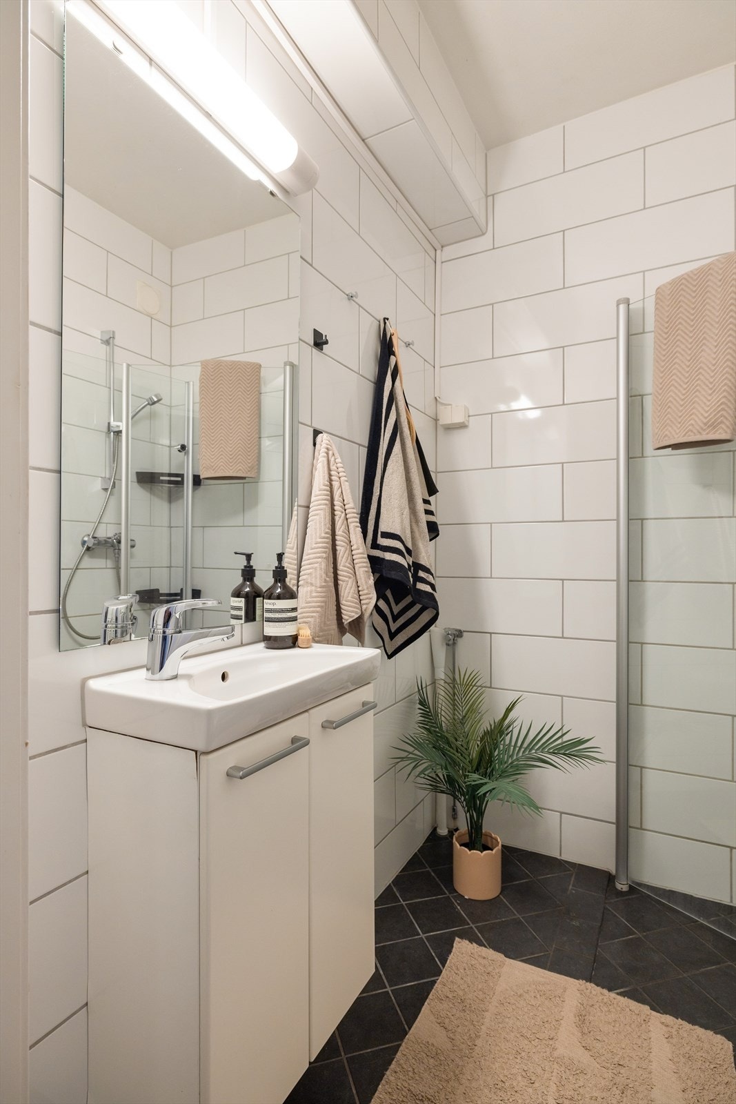 Badet er utstyrt med nedfelt servant, veggmontert toalett, dusjvegger/hjørne og opplegg for vaskemaskin. Galleribilde