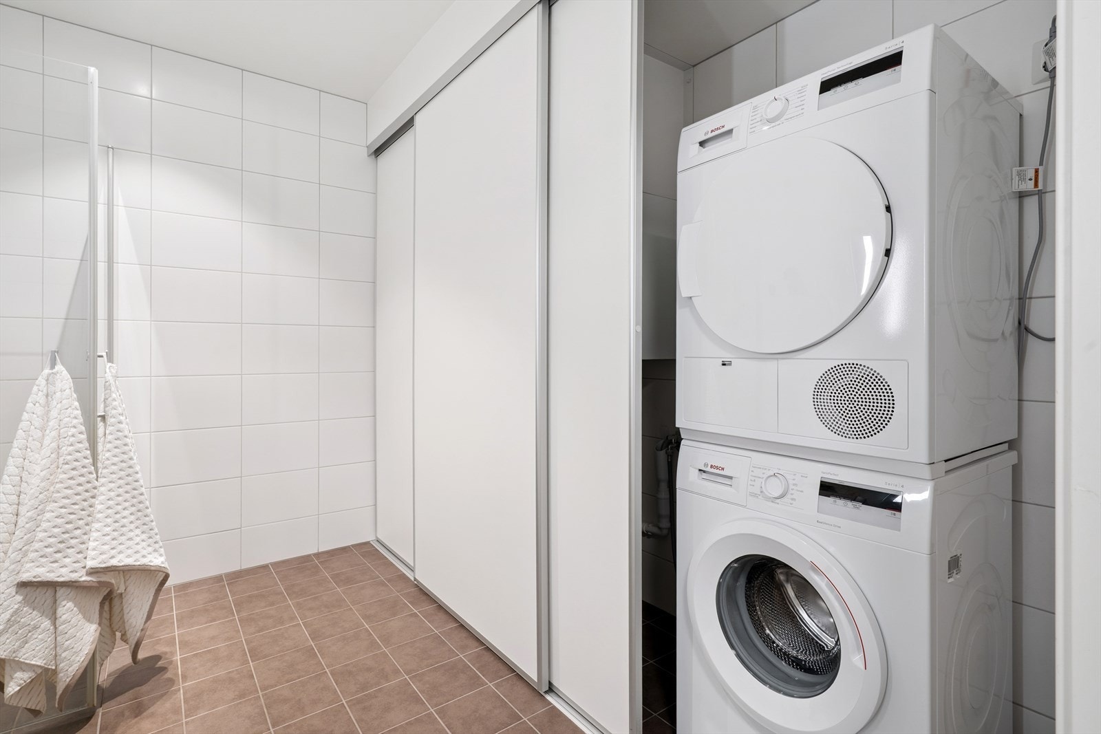 Bak en skyvedørsgarderobe er det et praktisk opplegg for vaskemaskin og tørketrommel. Galleribilde