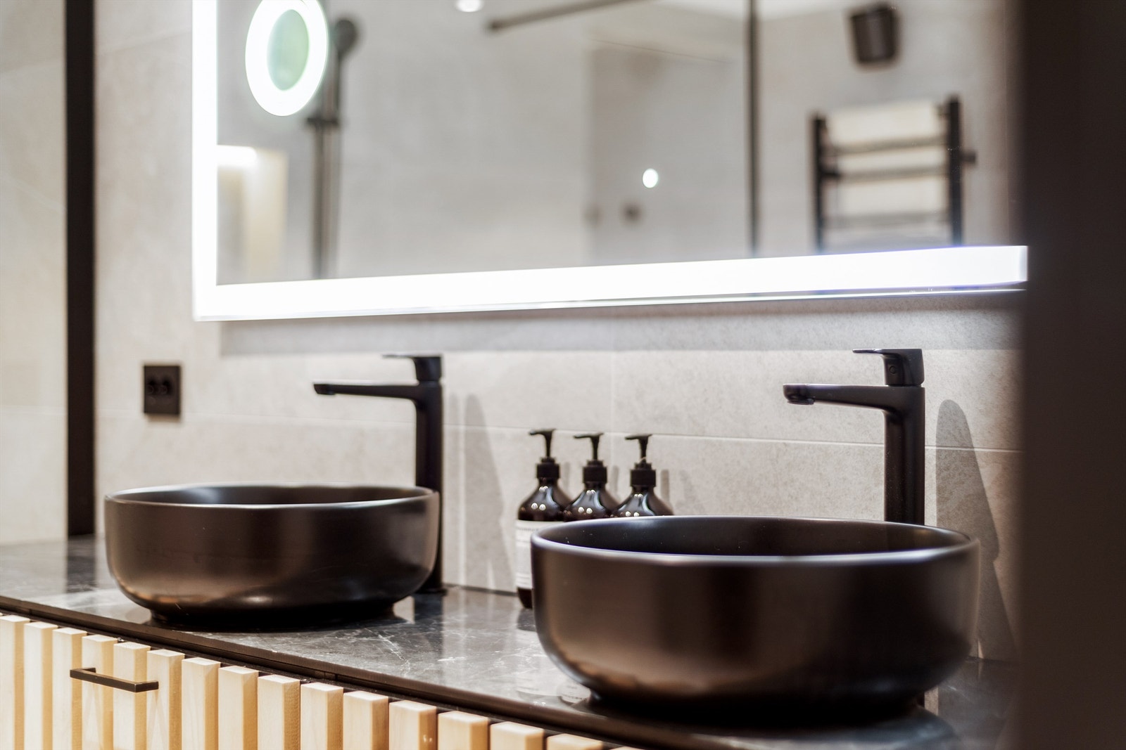 Baderomsinnredningen har spilefronter og flislagt benkeplate med doble servantboller Galleribilde