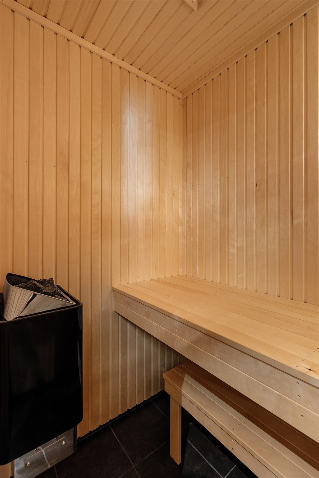 Badstuen har flislagt gulv, panel på vegger og tak, samt plassbygd innredning som gir både funksjon og komfort. Galleribilde