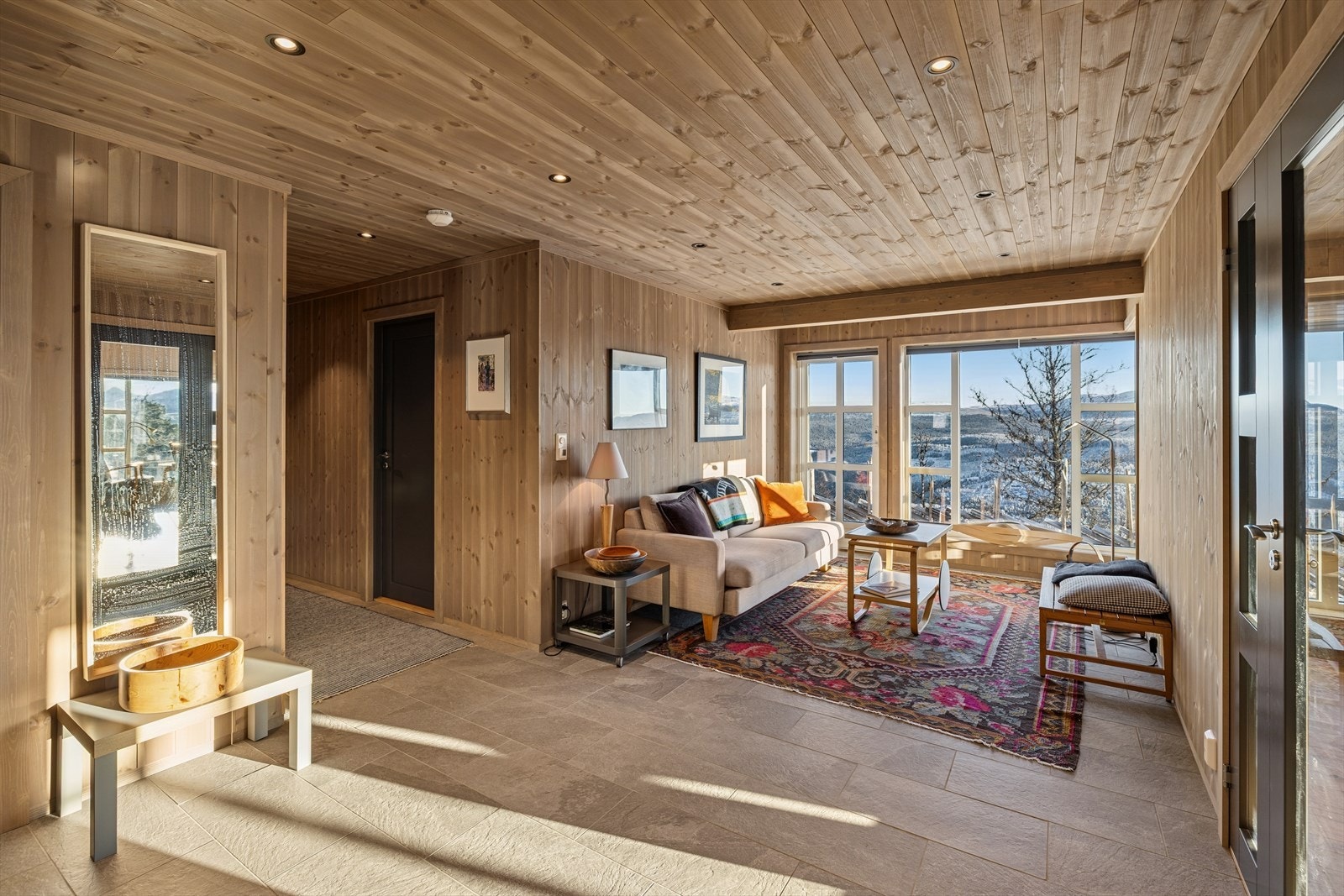 Entréen er flislagt med varme i gulvet og har en praktisk mellomstue. Her er det også spotter i taket og egen utgang til uteområdet - en funksjonell og velkomponert velkomstsone! Galleribilde