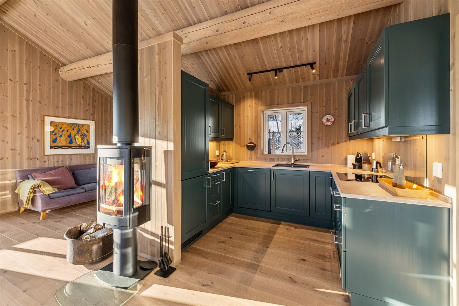 Hytta har en åpen stue- og kjøkkenløsning. Kjøkkenet har profilerte fronter og heltre benkeplate, som gir både funksjonalitet og en tidløs stil. Galleribilde