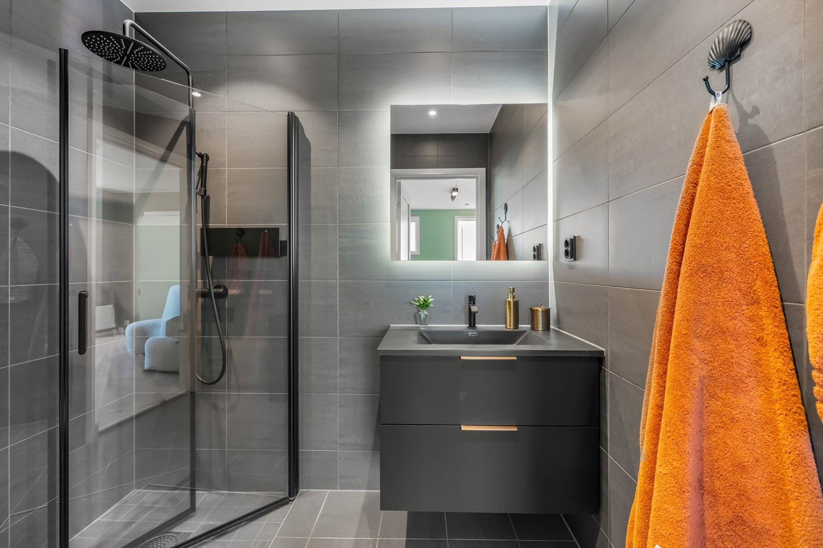 Badet er ellers innredet med dusjhjørne, vegghengt toalett og baderomsinnredning med nedfelt servant. Her er mørke detaljer gjennomgående, noe som skaper et eksklusivt uttrykk. Galleribilde