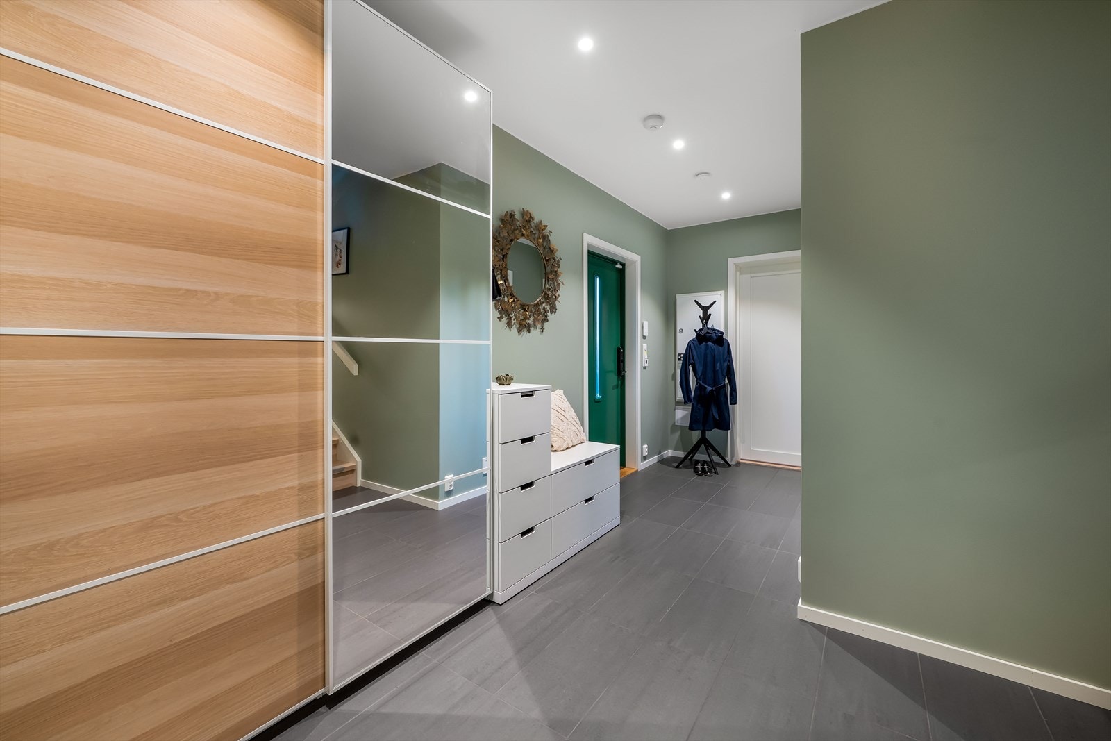 Man ønskes velkommen inn i en lys og romslig entré i boligens første etasje som er praktisk innredet med flislagt gulv og stor skyvedørsgarderobe hvor man har god plass til familiens yttertøy. Galleribilde