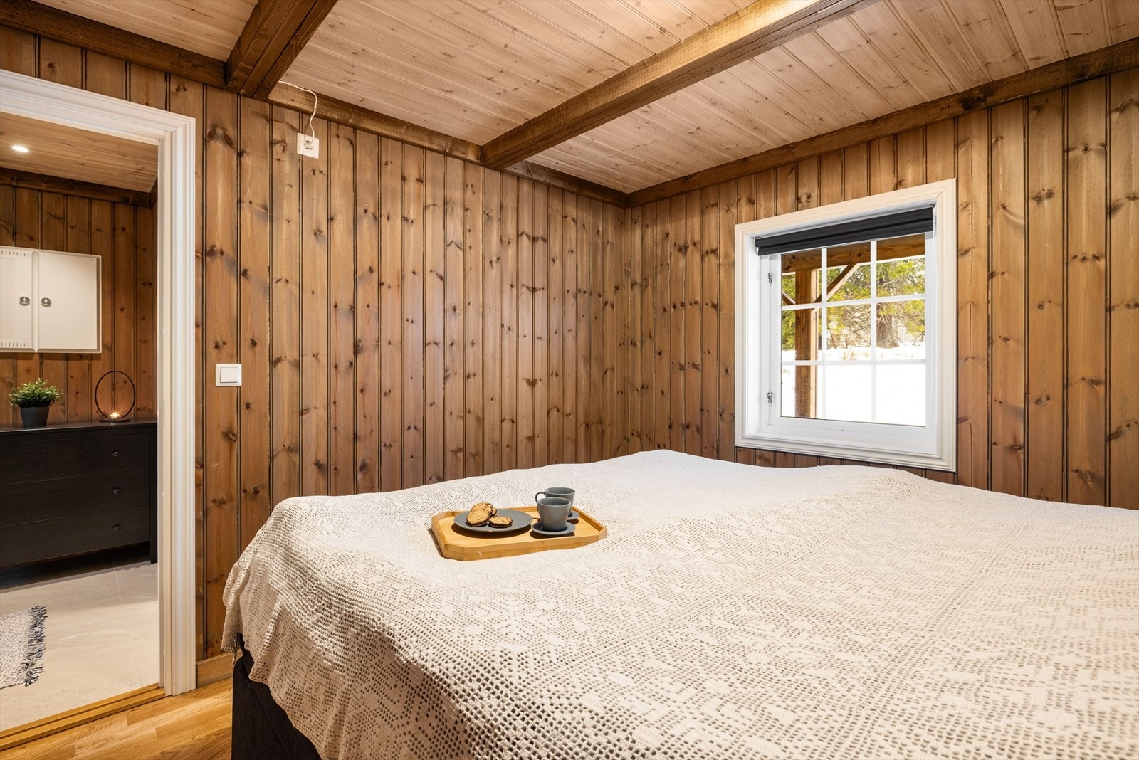 Soverommet har parkett på gulv, lun trepanel på veggene og vindu ut mot baksiden av hytta. Galleribilde