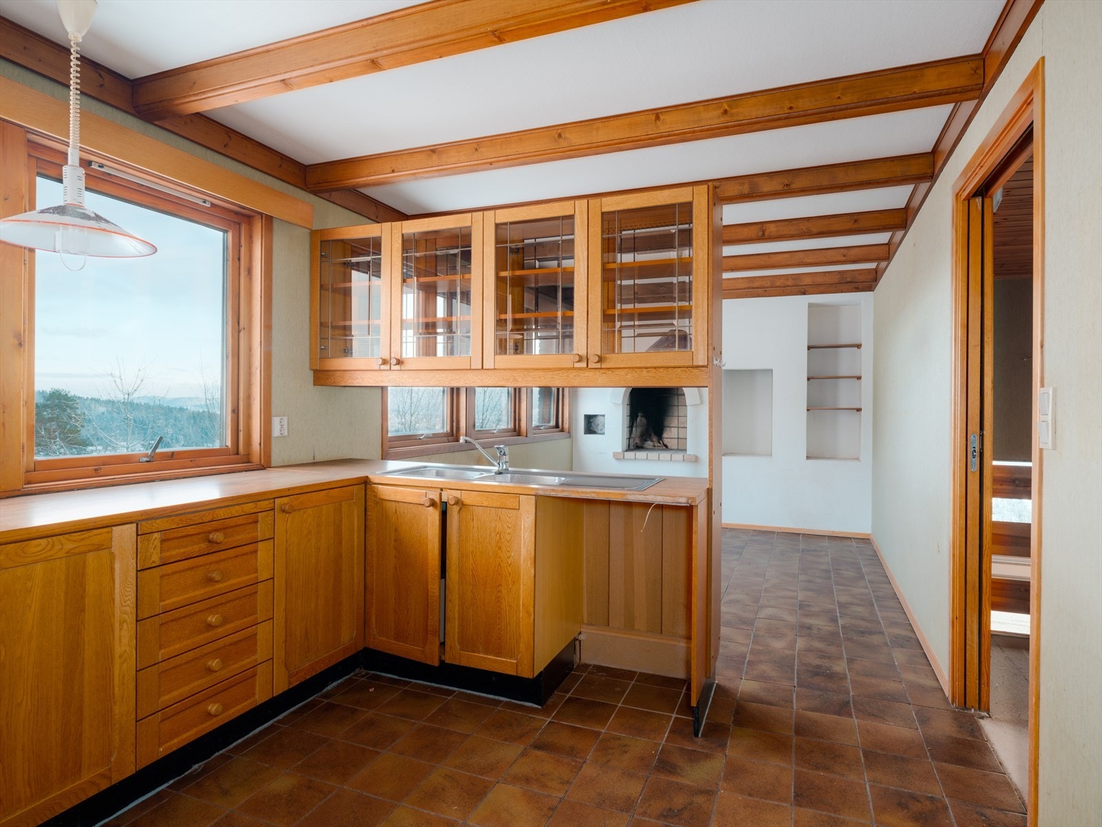 Stort kjøkken med spiseavdeling, åpen peis og langstrakt utsikt fra store vindusflater Galleribilde