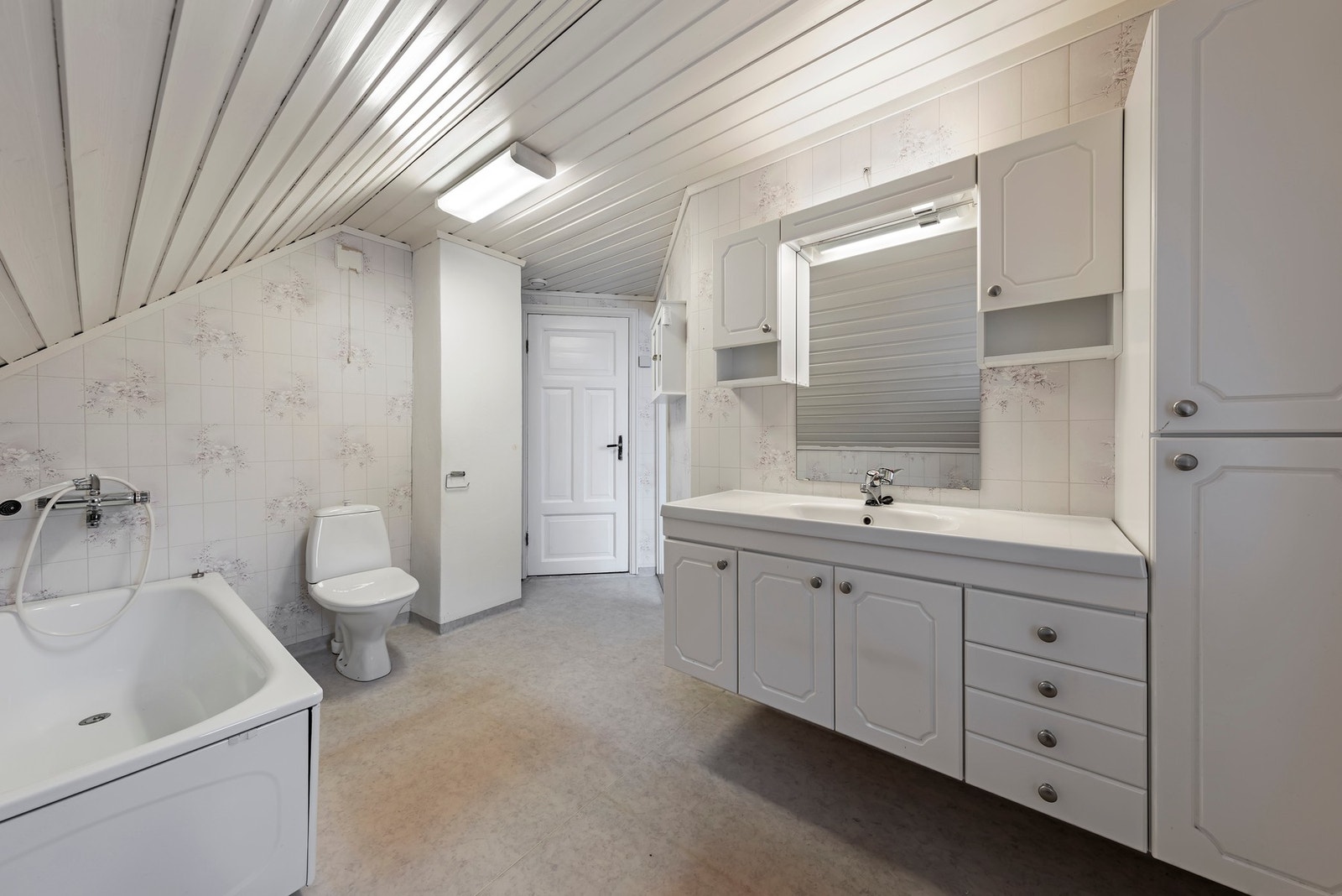 Badet har gulv med vinylbelegg og elektriske varmekabler. Baderominnredning med heldekkende servant, badekar og gulvmontert toalett Galleribilde