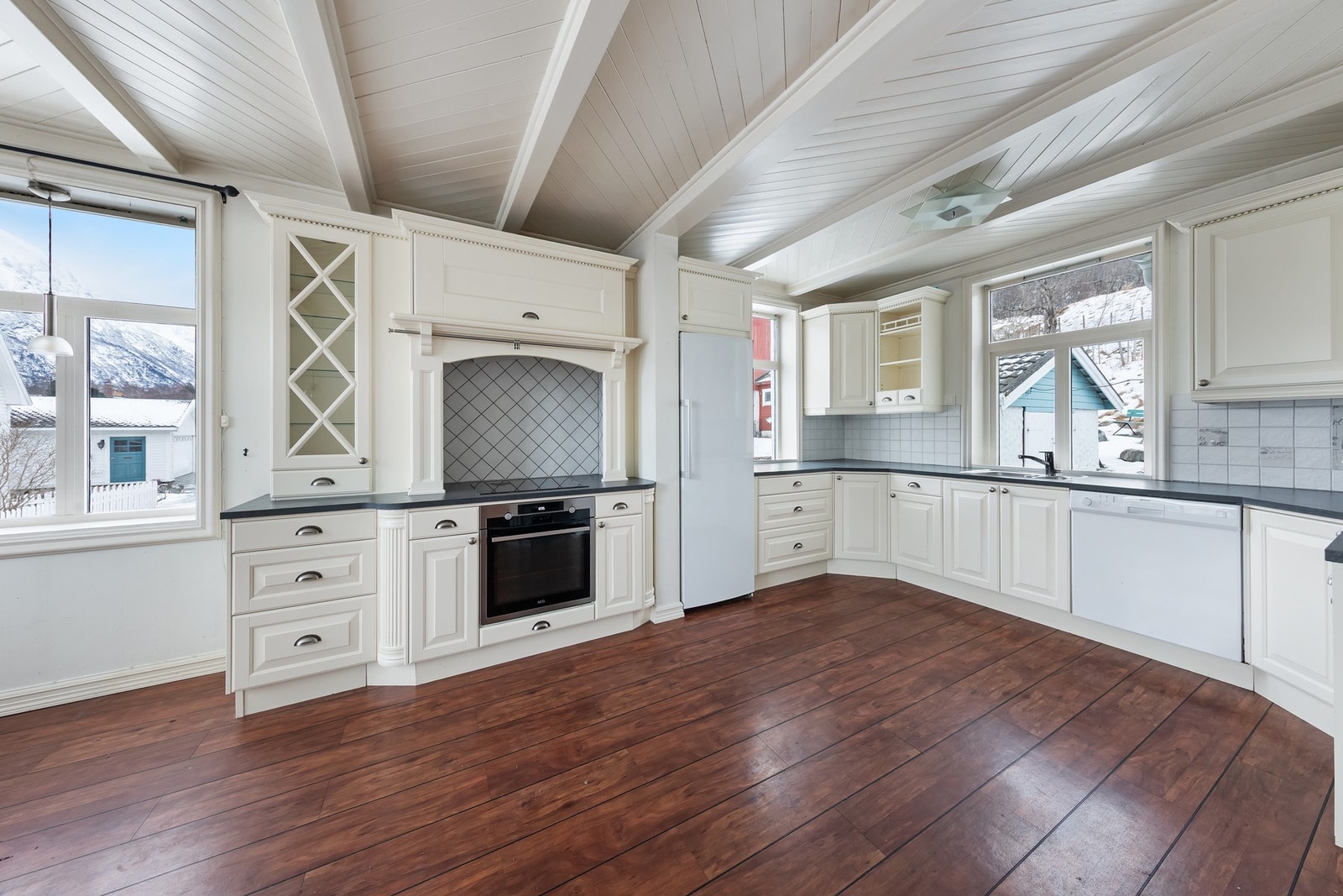 Kjøkkeninnredning med malte profilerte fronter/dører og benkeplater i laminat. Integrerte hvitevarer som induksjonstopp, stekeovn og oppvaskmaskin. Frittstående kjøleskap Galleribilde