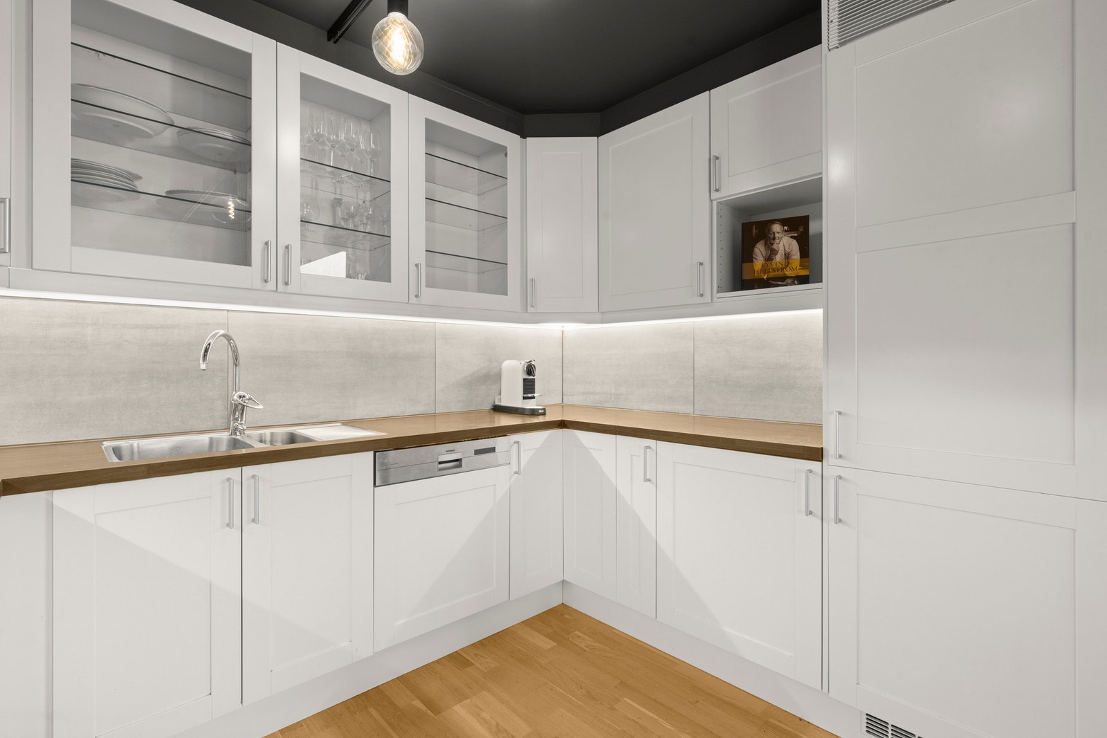 Kjøkkenet byr på integrerte hvitevarer som induksjonstopp, komfyr, oppvaskmaskin og kjøleskap med frysedel. Galleribilde