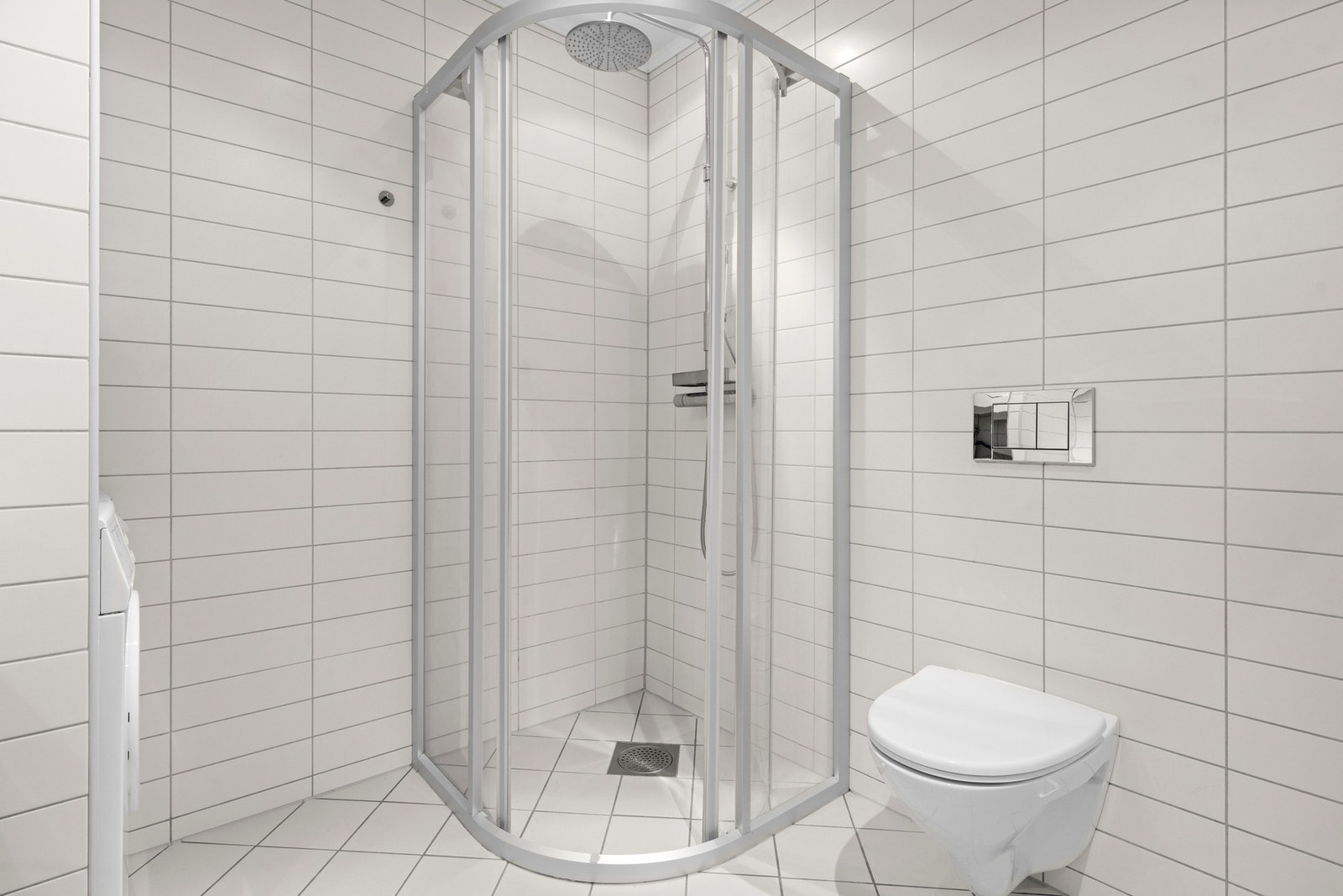 Innredningen består av servantinnredning, speil på vegg over servant, vegghengt toalett og skjermet dusjhjørne. Galleribilde