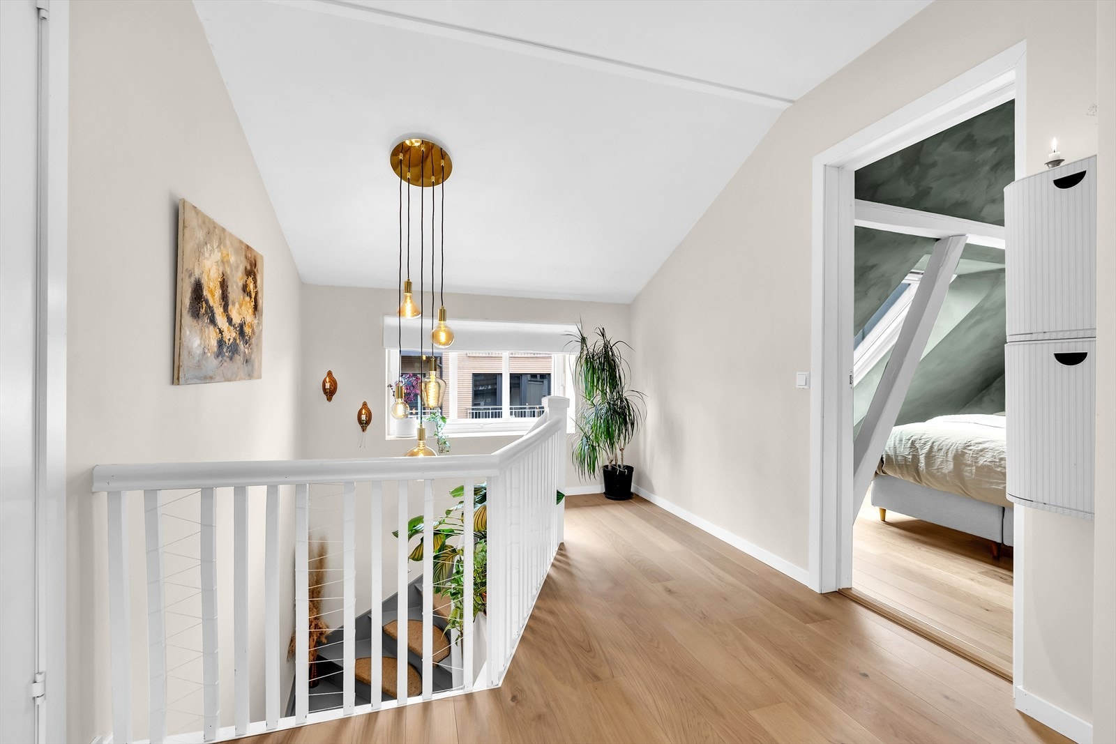 Lys og åpen loftsgang med eikeparkett og god takhøyde - herfra er det adkomst til begge soverom. Dekorativ belysning og vindu mot trapperommet gir rommet en luftig følelse. Galleribilde