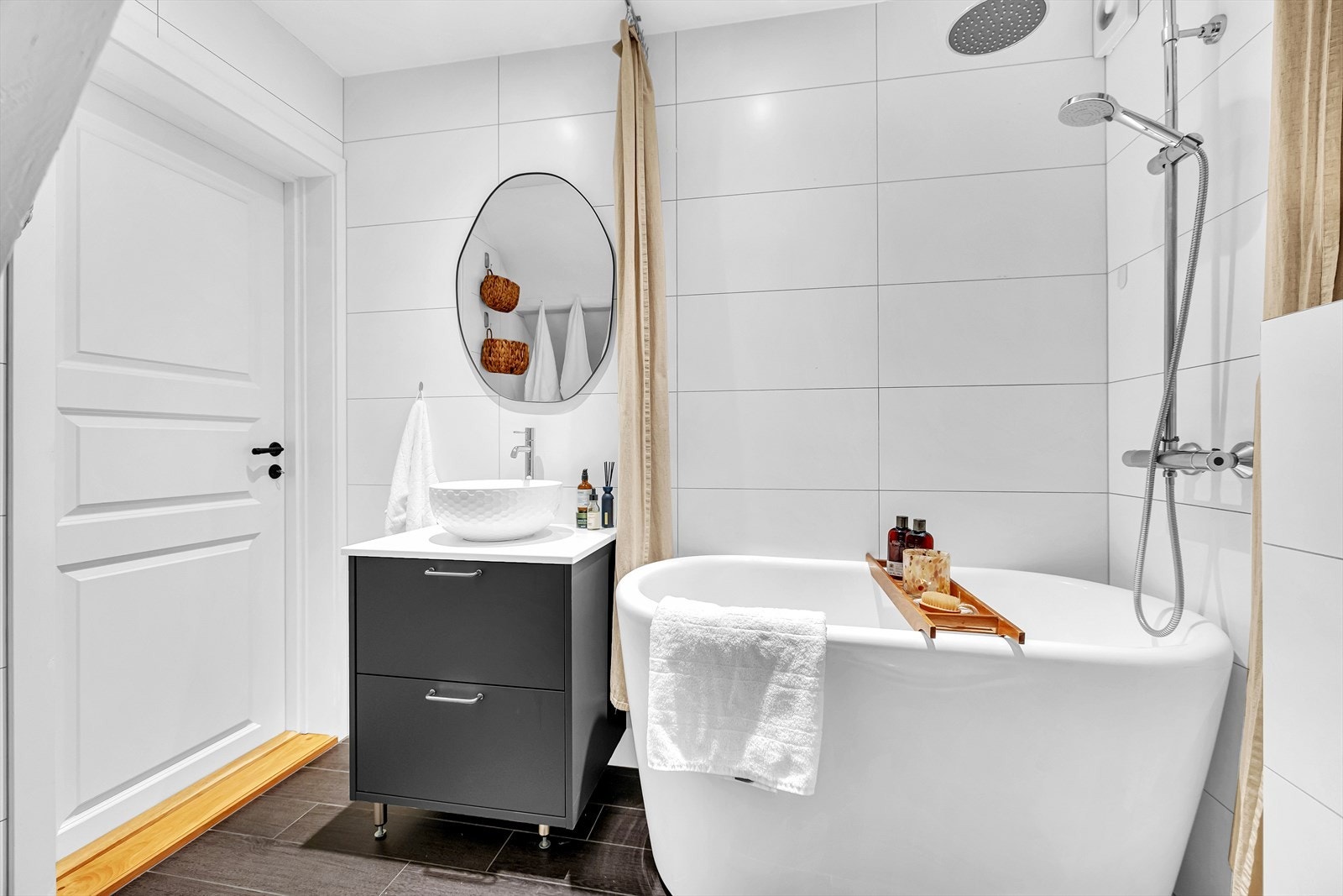 Rommet kombinerer velvære og funksjon med både baderomsfasiliteter og vaskemuligheter. Vegghengt toalett og mørke gulvfliser gir et helhetlig og tidsriktig uttrykk. Galleribilde