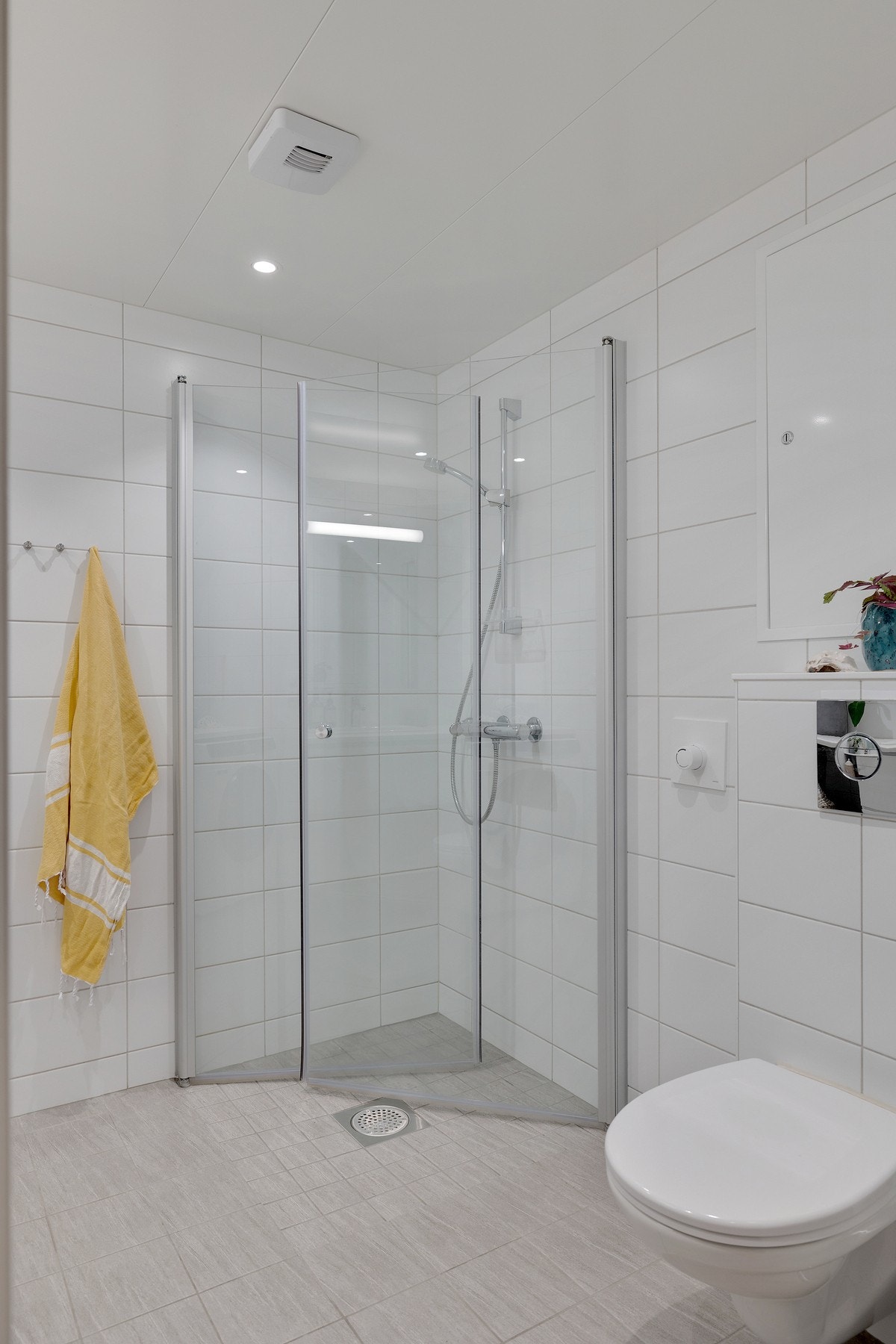 Innredning med innfellbare dusjdører i glass og vegghengt toalett Galleribilde