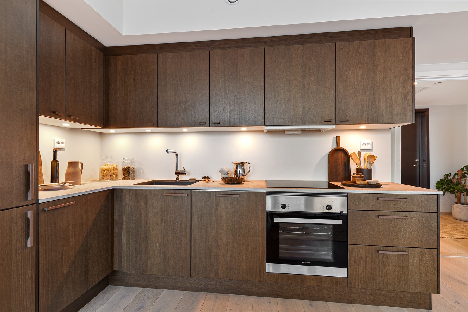 Innredningen har moderne fronter i beiset eik utførelse, kombinert med en fargemessig avstemt laminat benkeplate i steinimitasjon. Galleribilde