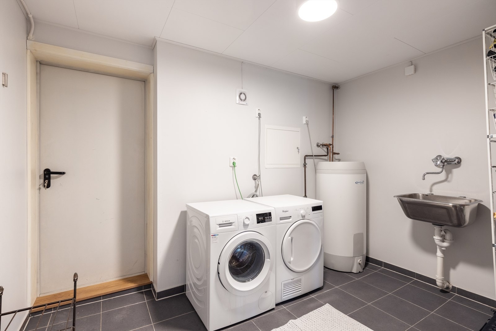 Vaskerommet er innredet med utslagsvask, varmtvannsbereder og opplegg for vaskemaskin. Rommet har praktisk adkomst til garasjen. Galleribilde