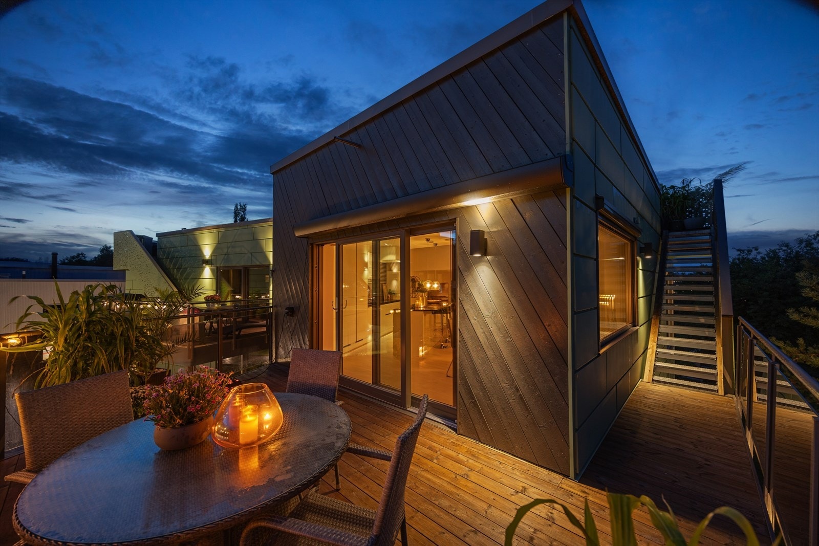 Kveldsstemning fra balkongen. Fellesområdet på inngansplan er belyst og oppleves som en lun oase. Galleribilde