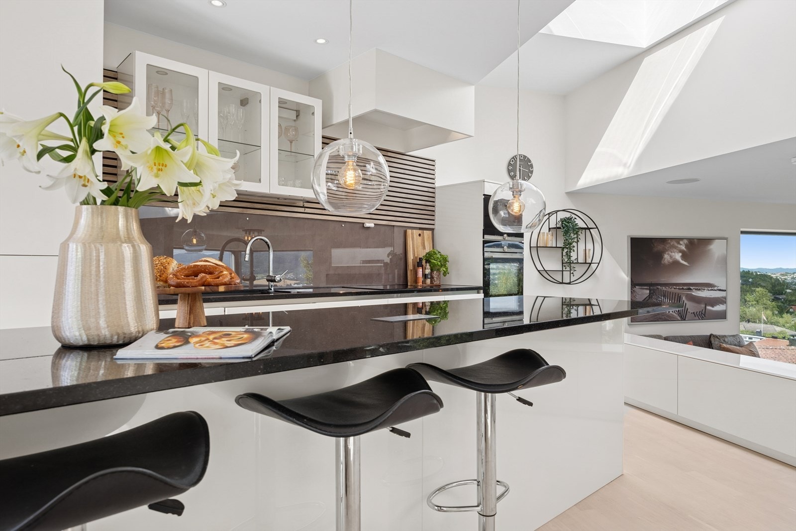 Nyt morgenkaffen ved kjøkkenbenken. Kjøkkenet har store benkeplater og dype skuffeseksjoner. Integrerte hvitevarer som kjøleskap, fryser, oppvaskmaskin, platetopp, stekeovn, ventilator og mikrobølgeovn. Galleribilde