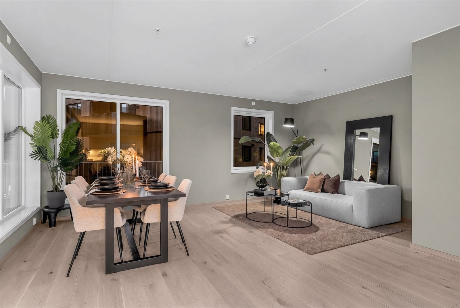 Lys og innbydende stue med åpen kjøkkenløsning og store vindusflater fra to sider som slipper inn rikelig med dagslys Galleribilde