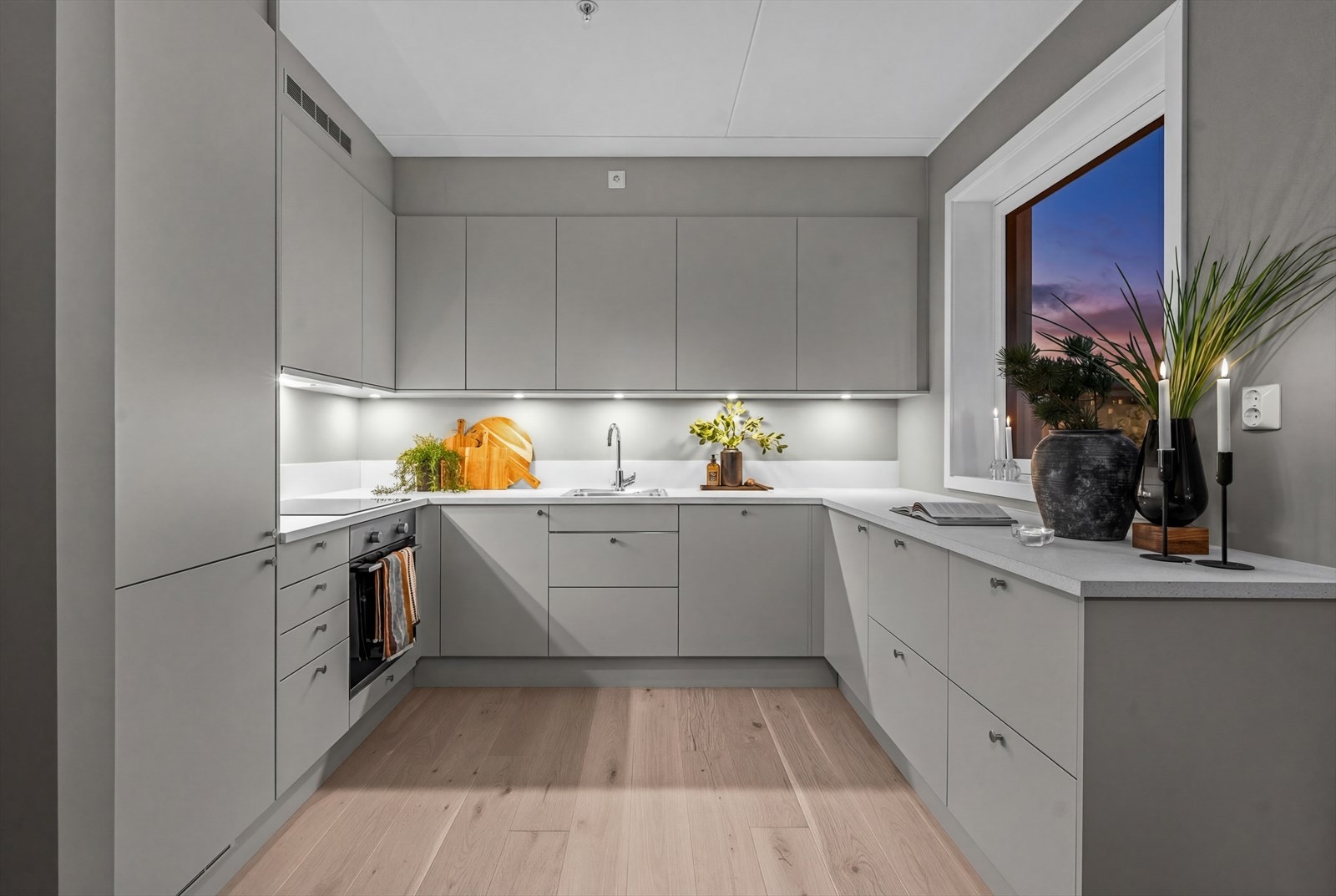 Kjøkkenet er stilrent utformet med laminatbenkeplate og utenpåliggende spotter under overskap som gir både godt arbeidslys og en lun stemning Galleribilde