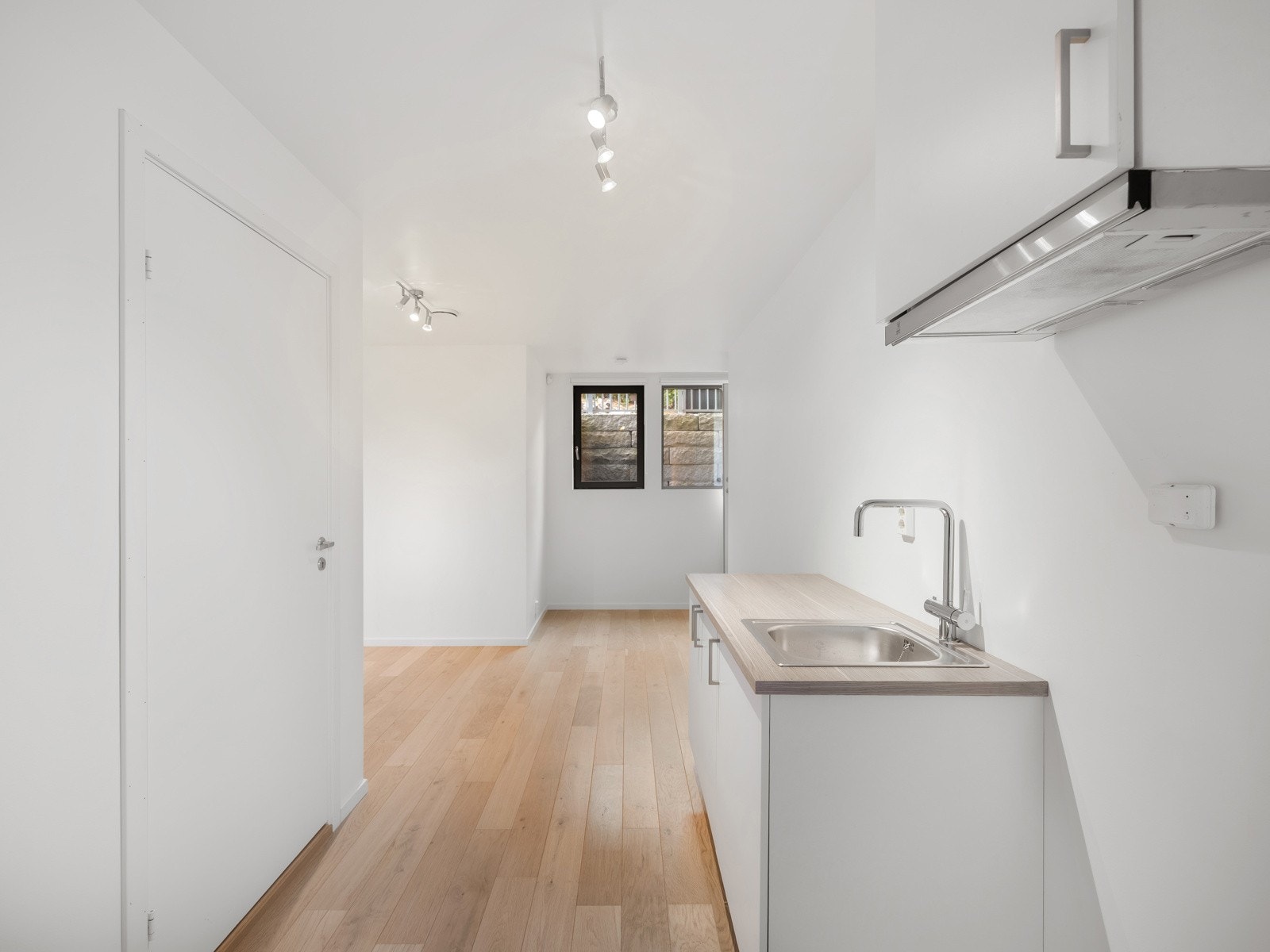 Kjøkkenet har hvite glatte fronter og laminatbenkeplate med stålkum og ettgreps blandebatteri. Galleribilde