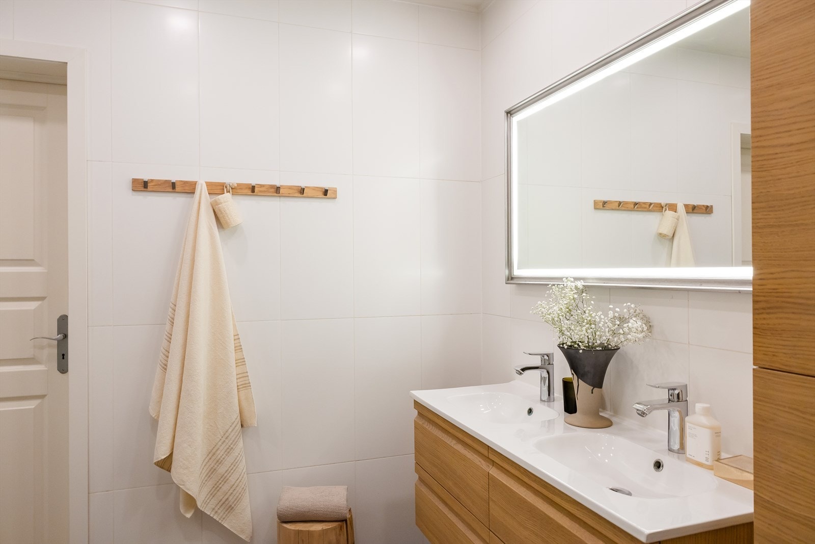 Badet er utstyrt med baderomsinnredning bestående av benkeskap og veggskap med glatte fronter, speil over servant, dusj med faste felt og dør i herdet glass, dobbel servant i helstøpt plate samt veggfestet klosett med innebygget sisterne. Galleribilde