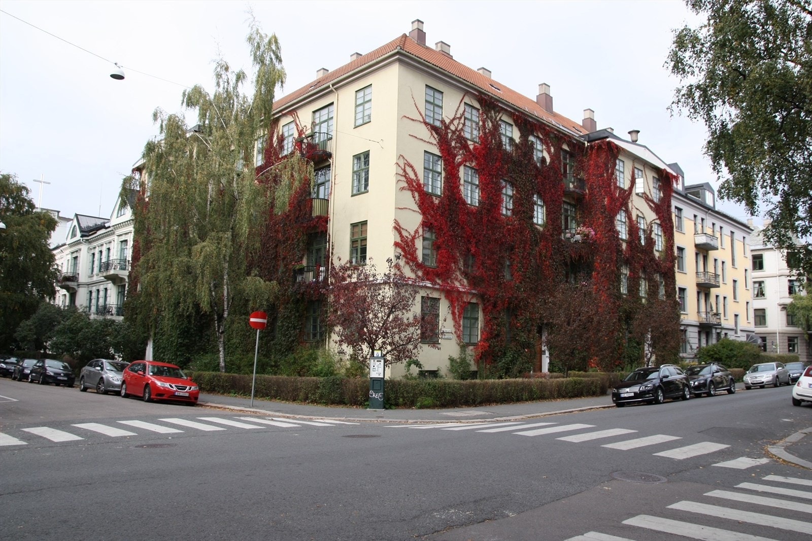 Sommerbilde tatt av selger som viser byggets flotte og karakteristiske fasade, omkranset av frodig beplantning. Galleribilde