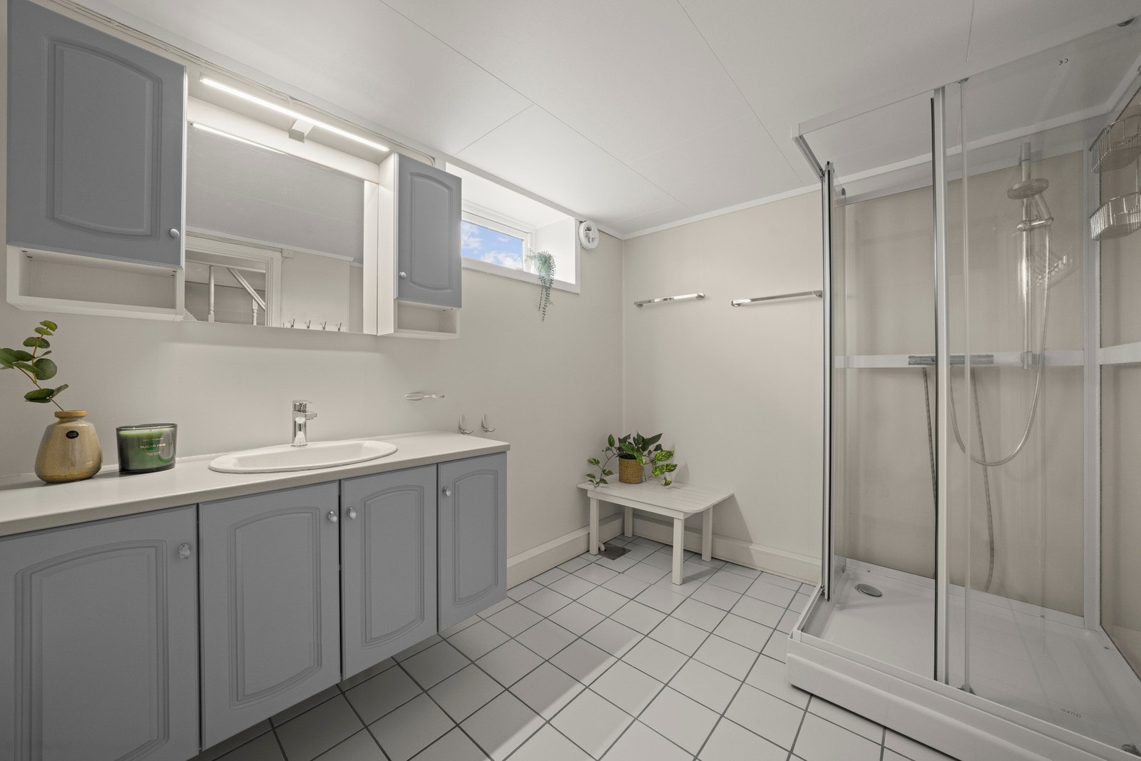 Badet i underetasjen har flislagt gulv, malte vegger og enkel innredning med servant, toalett og dusjkabinett. Galleribilde