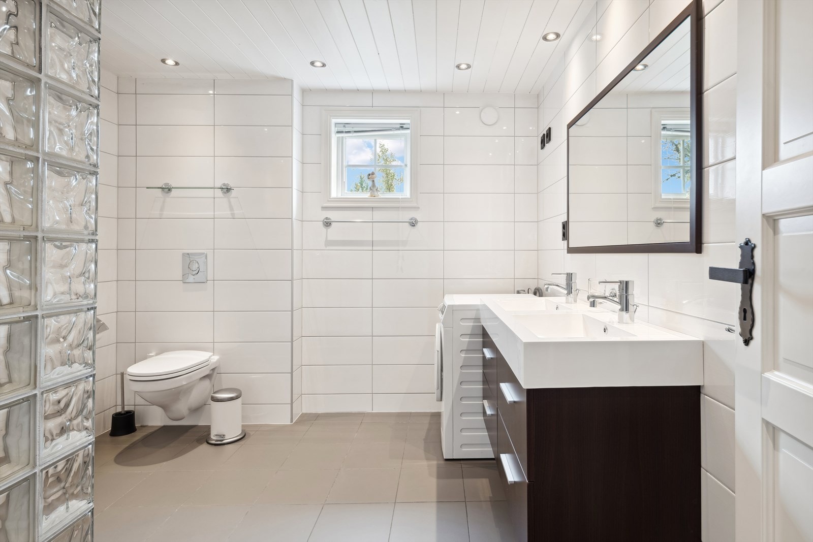 Romslig flislagt bad som fremstår sofistikert og pent. Galleribilde