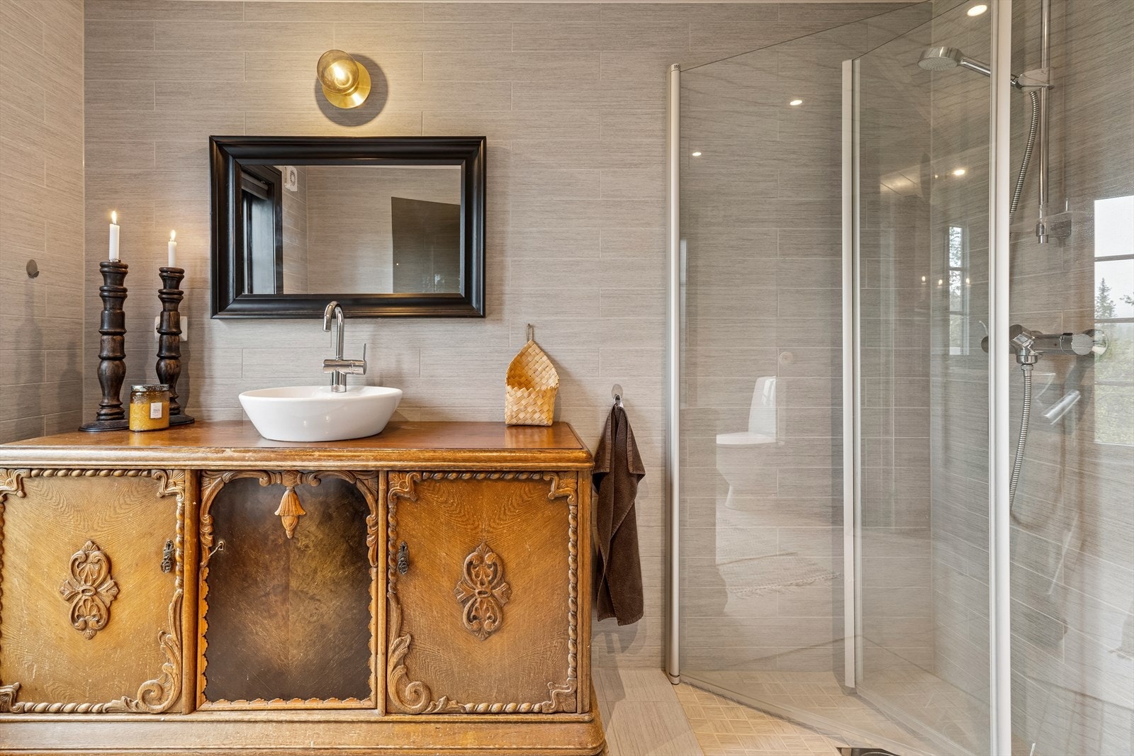 Badet er helfliset med lyse delikate fliser og har dusjhjørne med innfellbare dører. Galleribilde