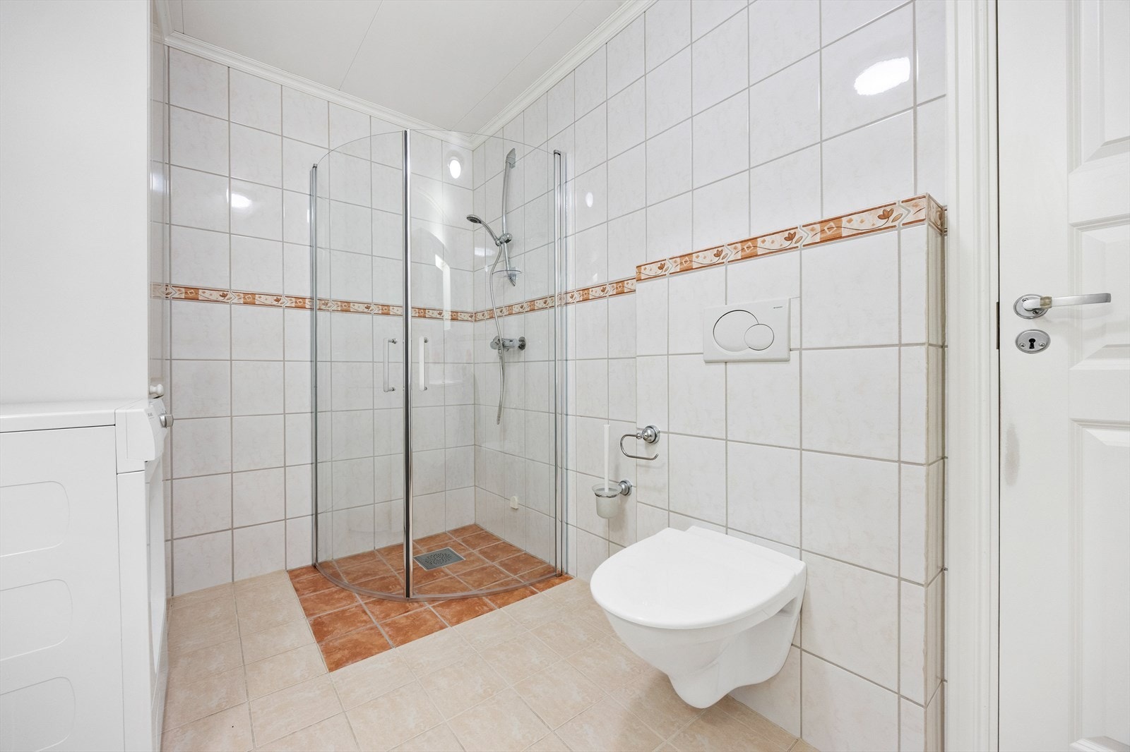 Videre har badet veggmontert toalett, dusjhjørne med innfellbare glassdører og opplegg for vaskemaskin. Galleribilde