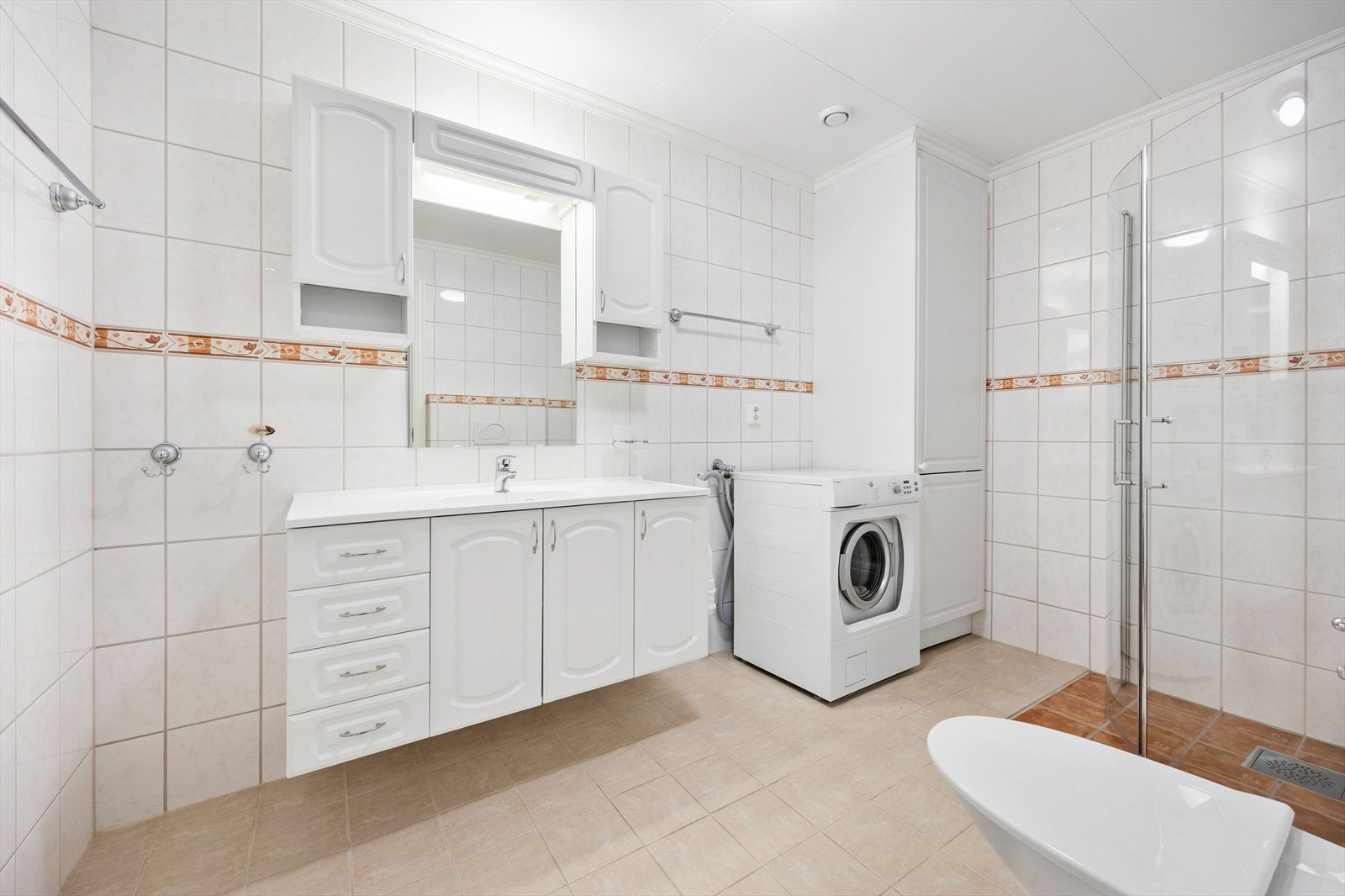 Det helflisede og romslige badet har godt med skap- og oppbevaringsplass og lun gulvvarme. Galleribilde