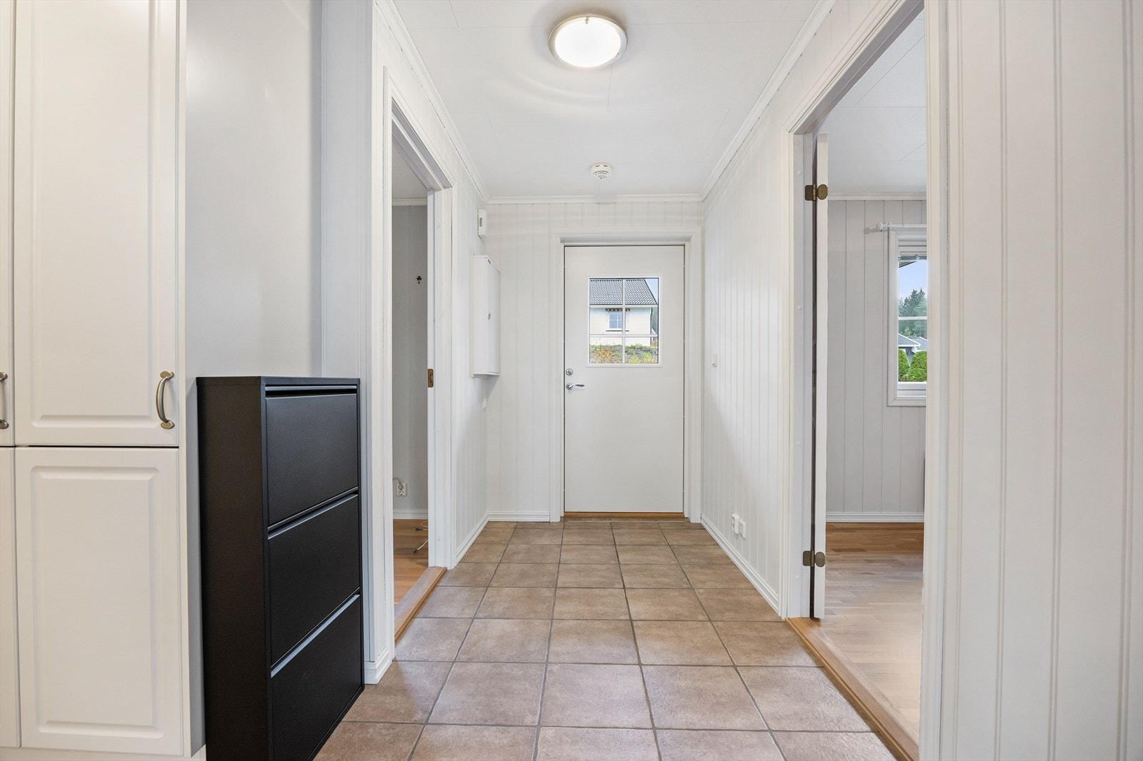 Entréen har hvitmalte MDF-plater med perlestaff på veggene og sandfargede fliser på gulvet med lun varme under. Galleribilde