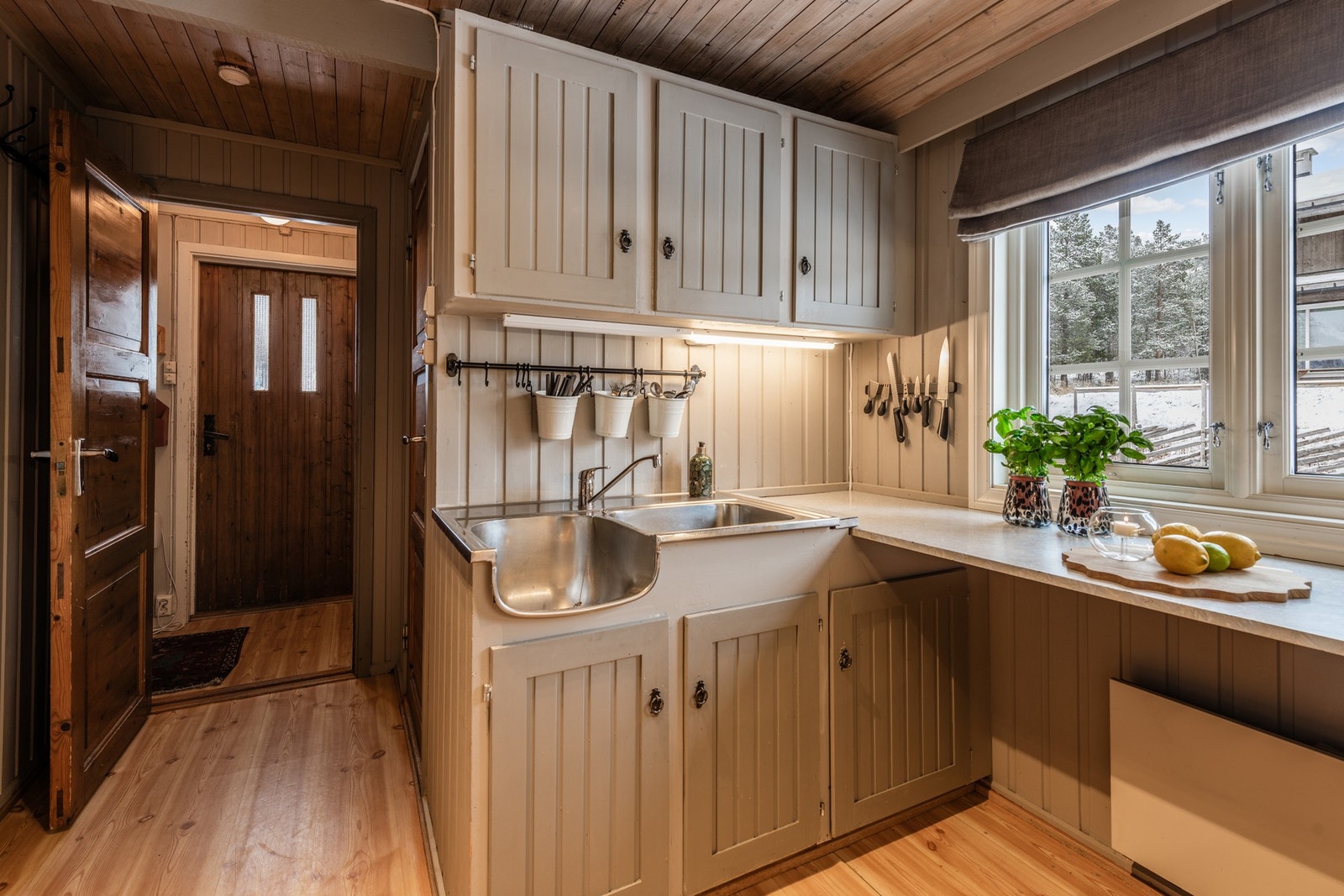 Enkel kjøkkeninnredning med oppvaskbenk, og over- og underskap. Galleribilde