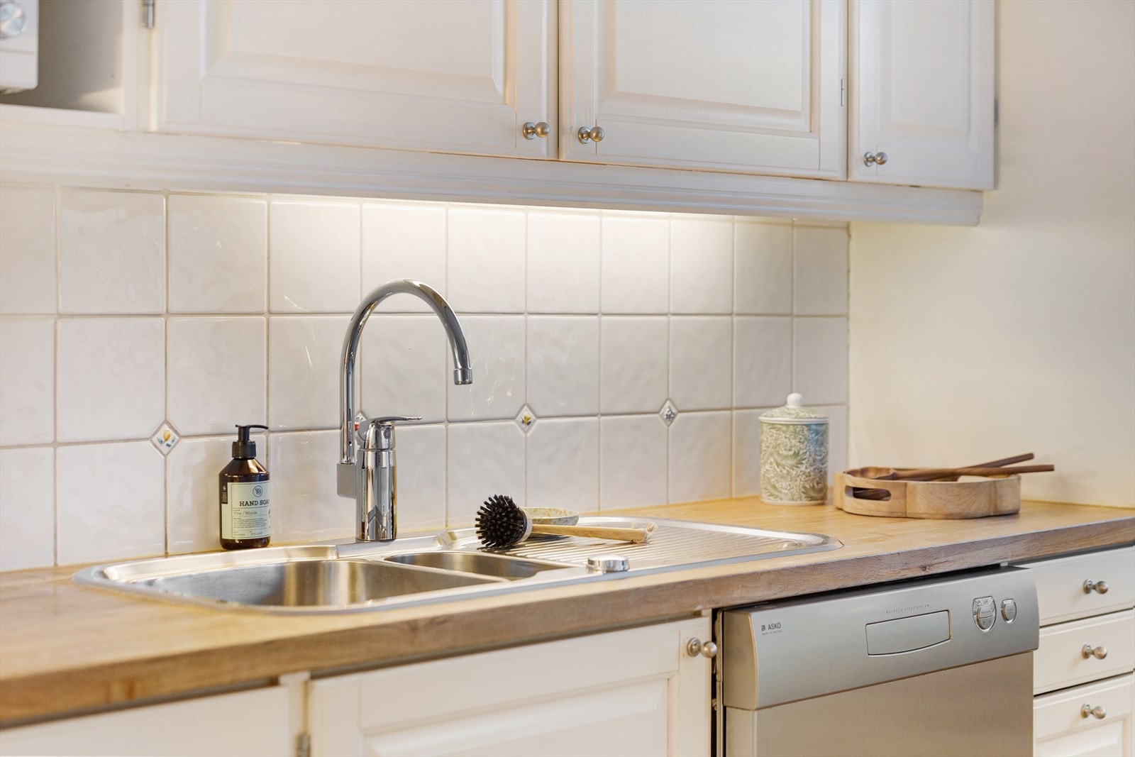 Fliser mellom benkeplate og overskap med belysning under. Galleribilde