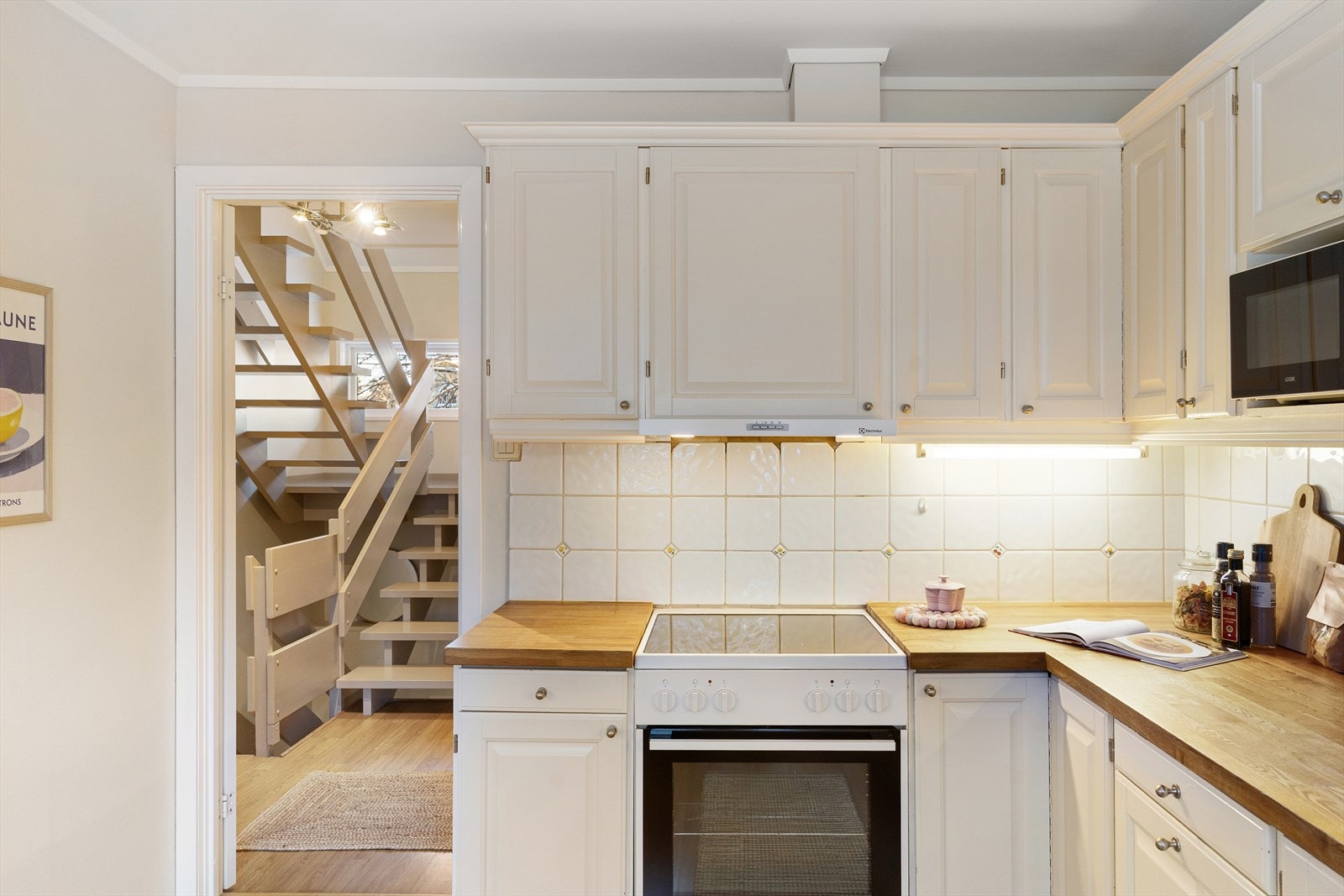 Kjøkken med profilerte fronter og benkeplate av heltre. Kjøkkenventilator med avtrekk ut. Galleribilde