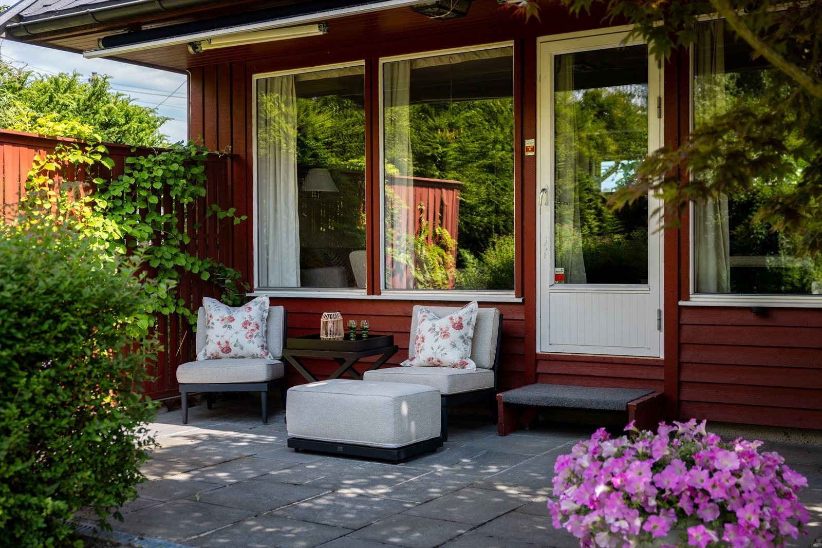 Terrasse i skifer-stein med utgang fra stuen. Her kan man nyte lyse dager om sommerhalvåret, skjermet fra omgivelsene, mens barna leker trygt i egen hage. Galleribilde