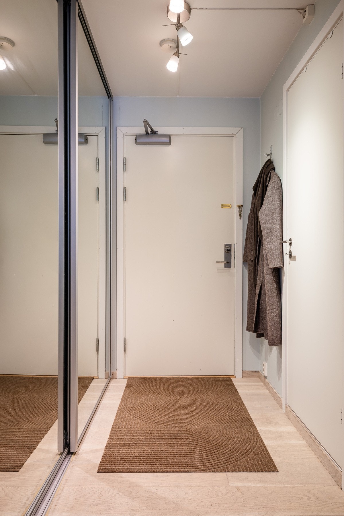 Boligen har trappefri og smidig adkomst fra indre gårdsrom. Entréen fremstår praktisk med skyvedørsgarderobe som gir god oppbevaringsplass Galleribilde