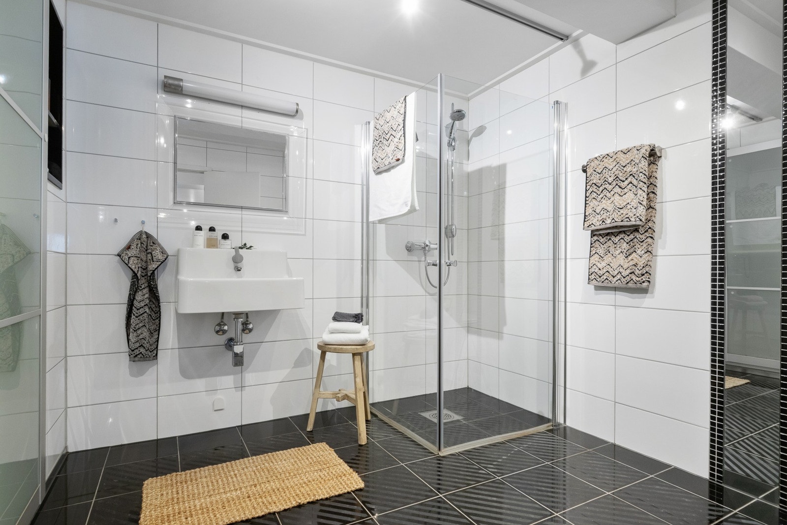 Badet er innredet med sorte gulvfliser og hvite veggfliser som gir en stilren kontrast. Galleribilde