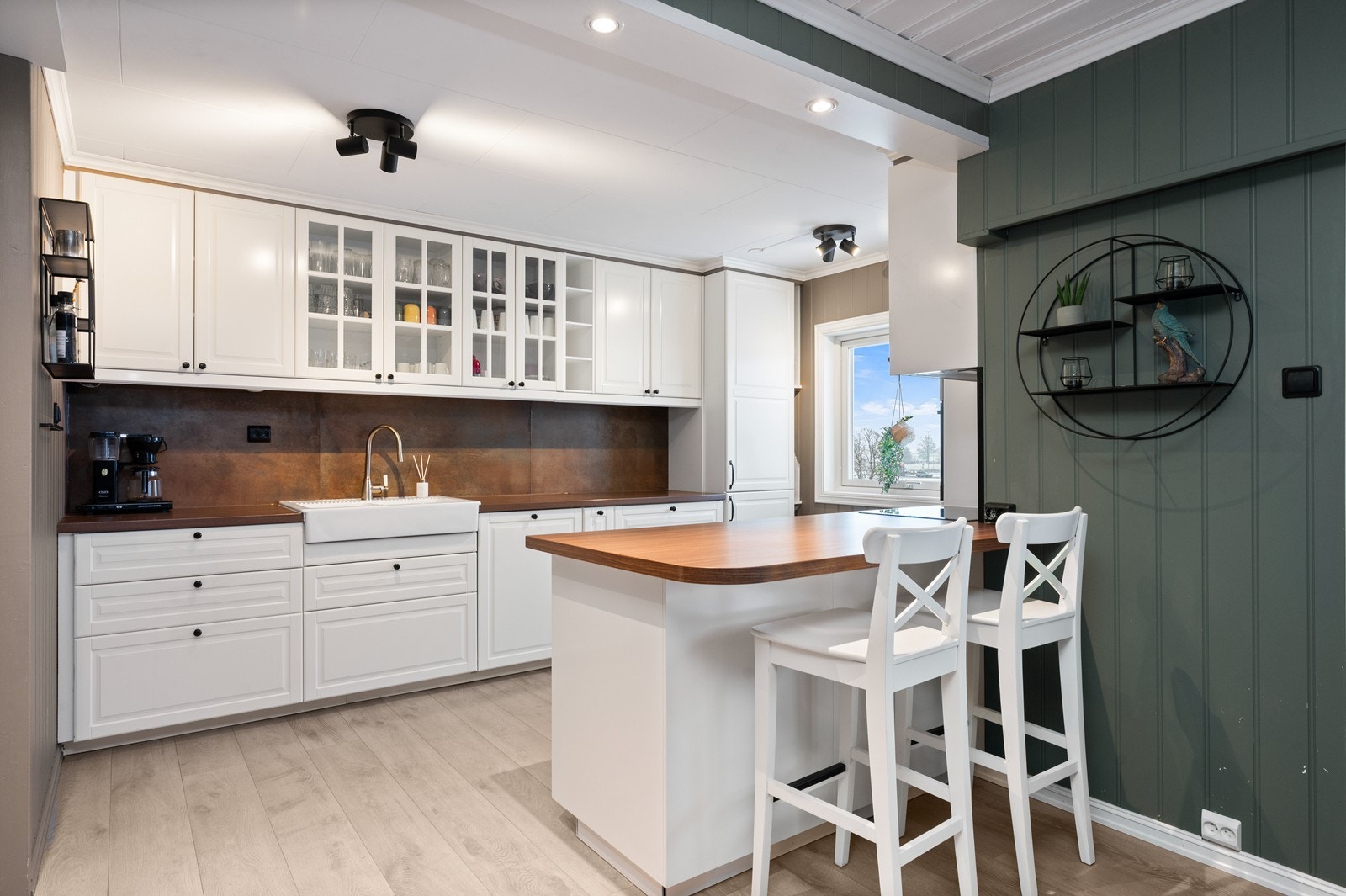 Kjøkkeninnredning med profilerte fronter, vitrineskap og en sosial kjøkkenhalvøy. Galleribilde