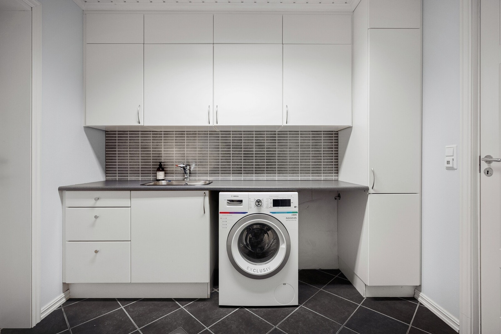 Praktisk vaskerom i underetasjen med flislagt gulv med gulvvarme. Galleribilde