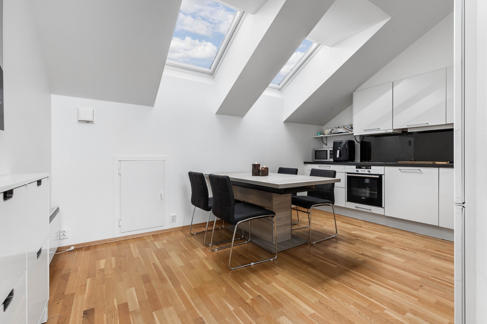 Mellom over- og underskap er det montert glassplate som gir et moderne uttrykk og er lett å holde rent. Kjøkkenet har plass til spisebord og danner en hyggelig ramme rundt både hverdagsmåltider og sosiale anledninger. Galleribilde