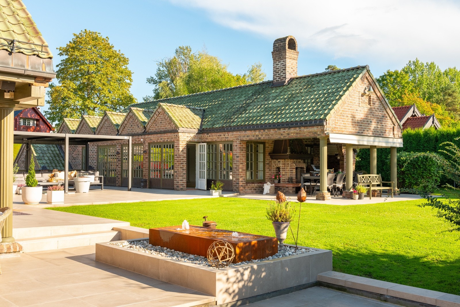 Mellom boligen og bassenghuset er det et fantastisk atrium med pergola, Sonos anlegg, varmelampe og fontene. Galleribilde