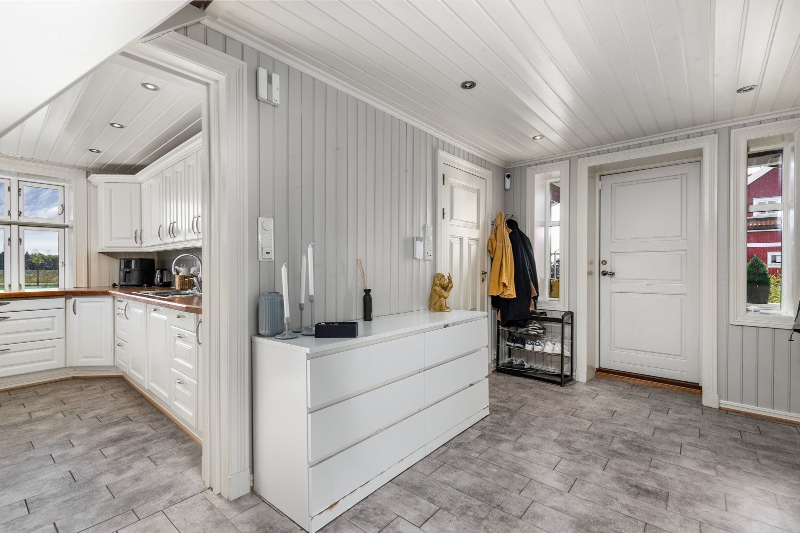 Romslig gang med flislagt gulv med gulvvarme og lyse panelvegger, som gir et hyggelig førsteinntrykk av boligen. Galleribilde