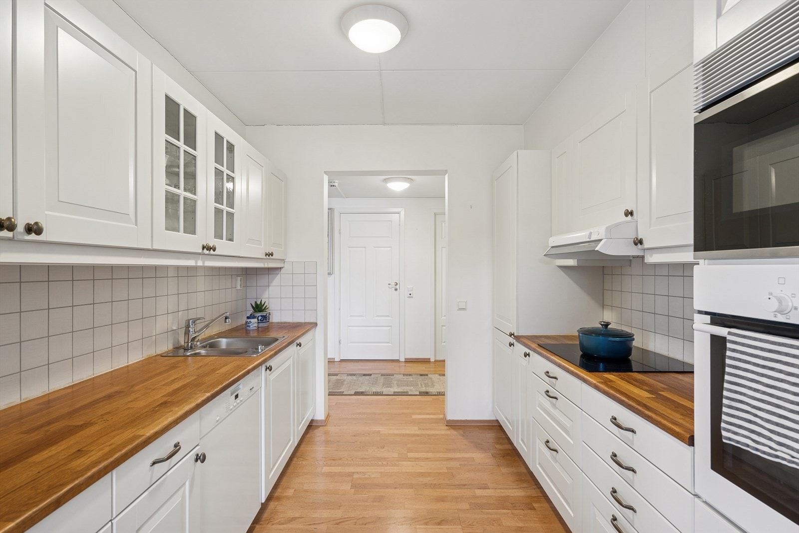 Innredning med hvite profilerte fronter og heltre benkeplate med nedfelt vaskekum Galleribilde